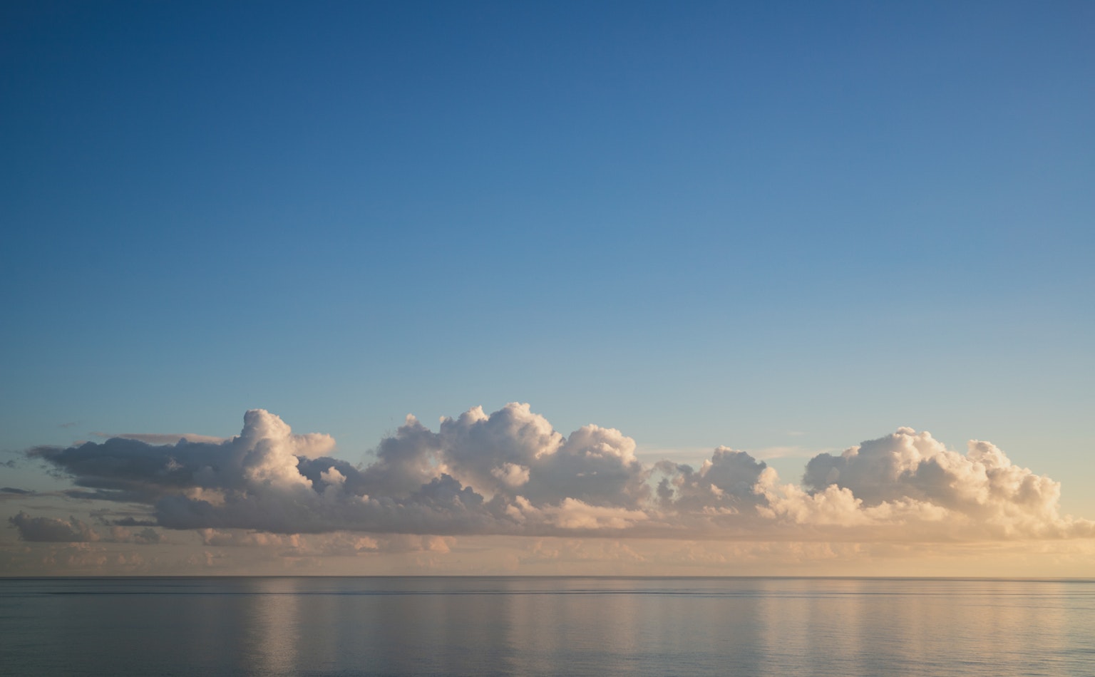 Un paesaggio sereno con nuvole bianche che galleggiano su un mare calmo sotto un cielo blu