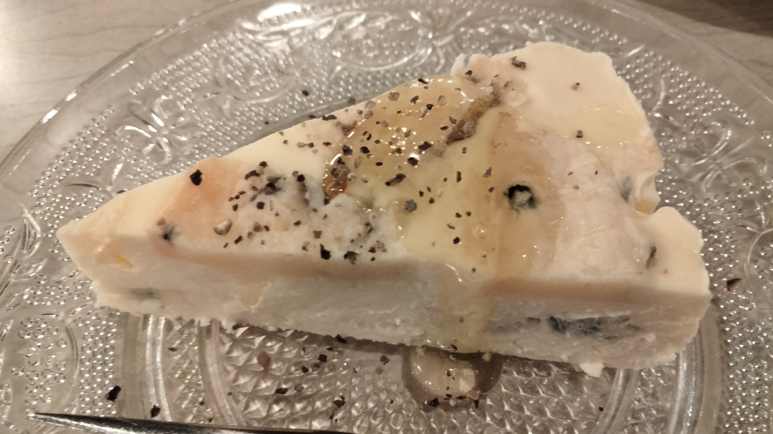 一片奶油起司蛋糕放在透明裝飾盤上