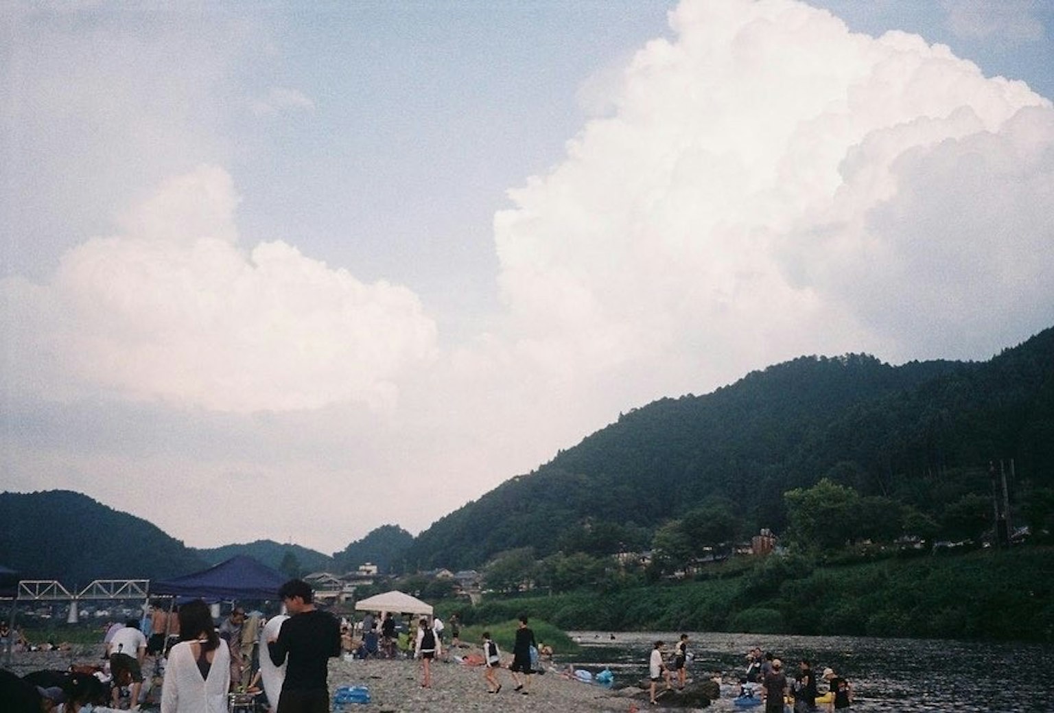 人們聚集在河邊藍天和白雲綠色山脈在背景