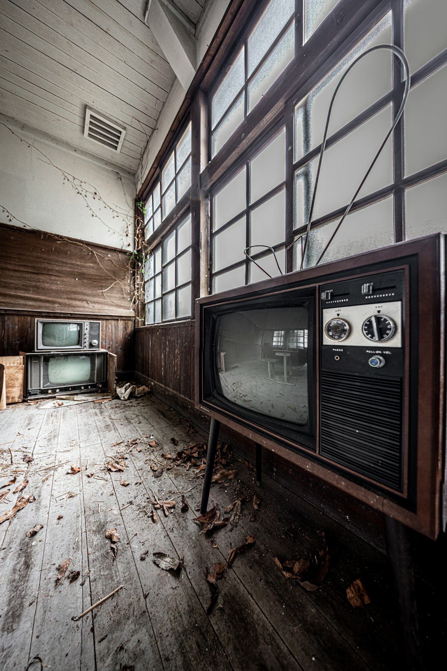 Old television in an abandoned room with dusty floor and windows