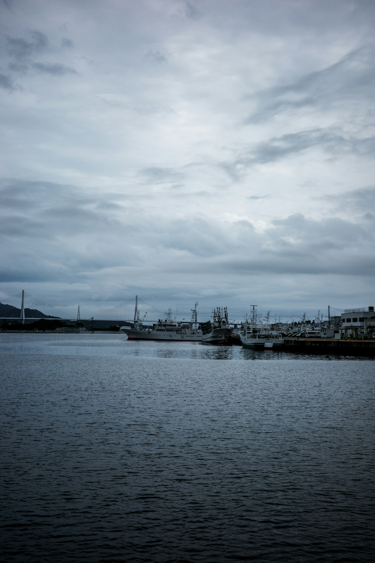 Scena di porto calma sotto un cielo nuvoloso con barche e acqua riflettente