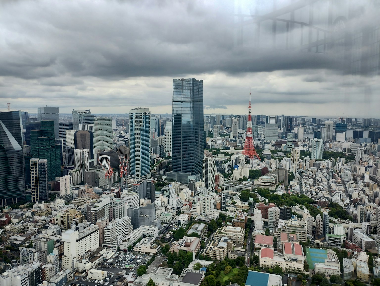 Blick auf die Skyline von Tokio mit Wolkenkratzern und dem Tokyo Tower unter einem bewölkten Himmel