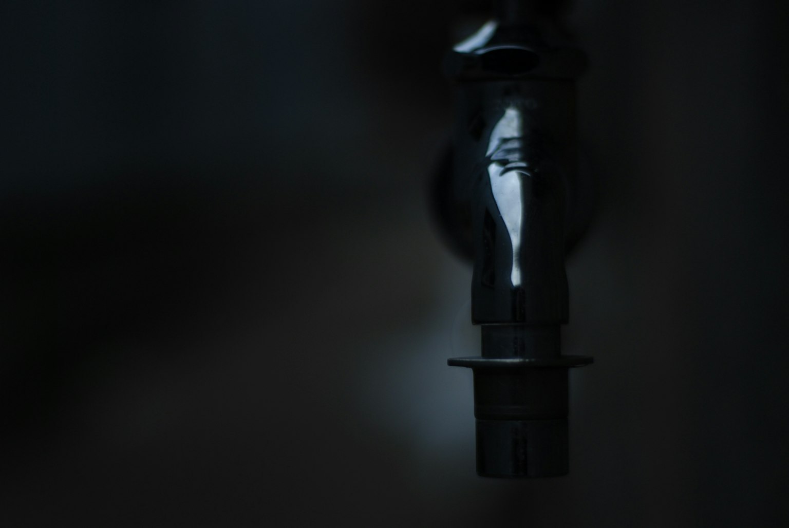 Close-up of a metallic faucet shining against a dark background