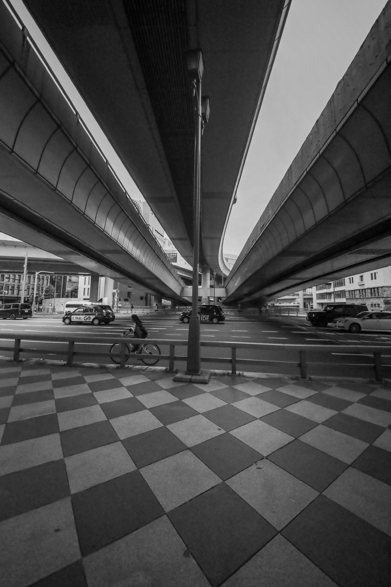 Checkered pavement under elevated roads with vehicles
