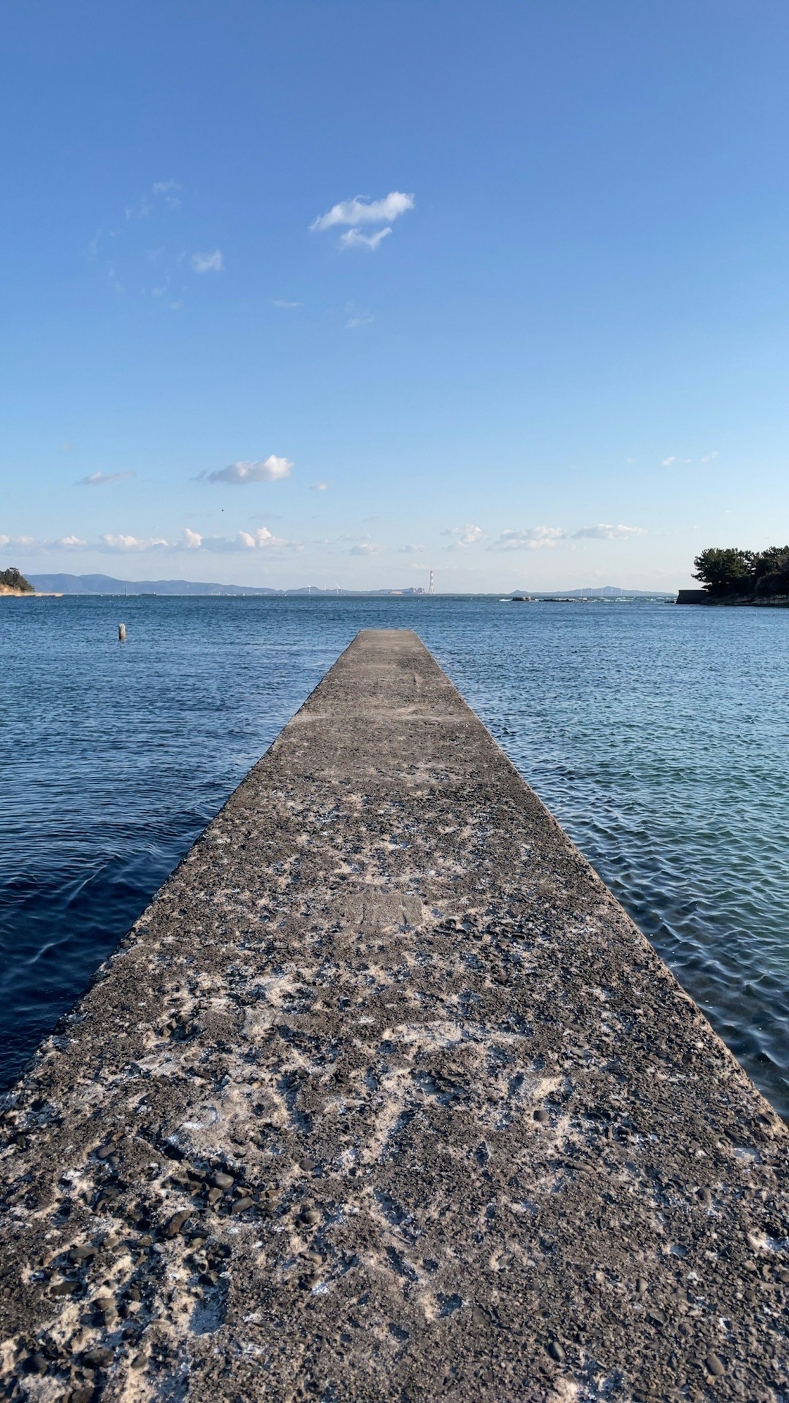 Dermaga beton yang membentang ke laut biru