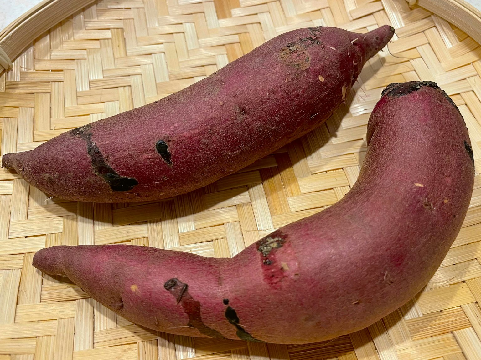 Due patate dolci viola posizionate su un cesto intrecciato