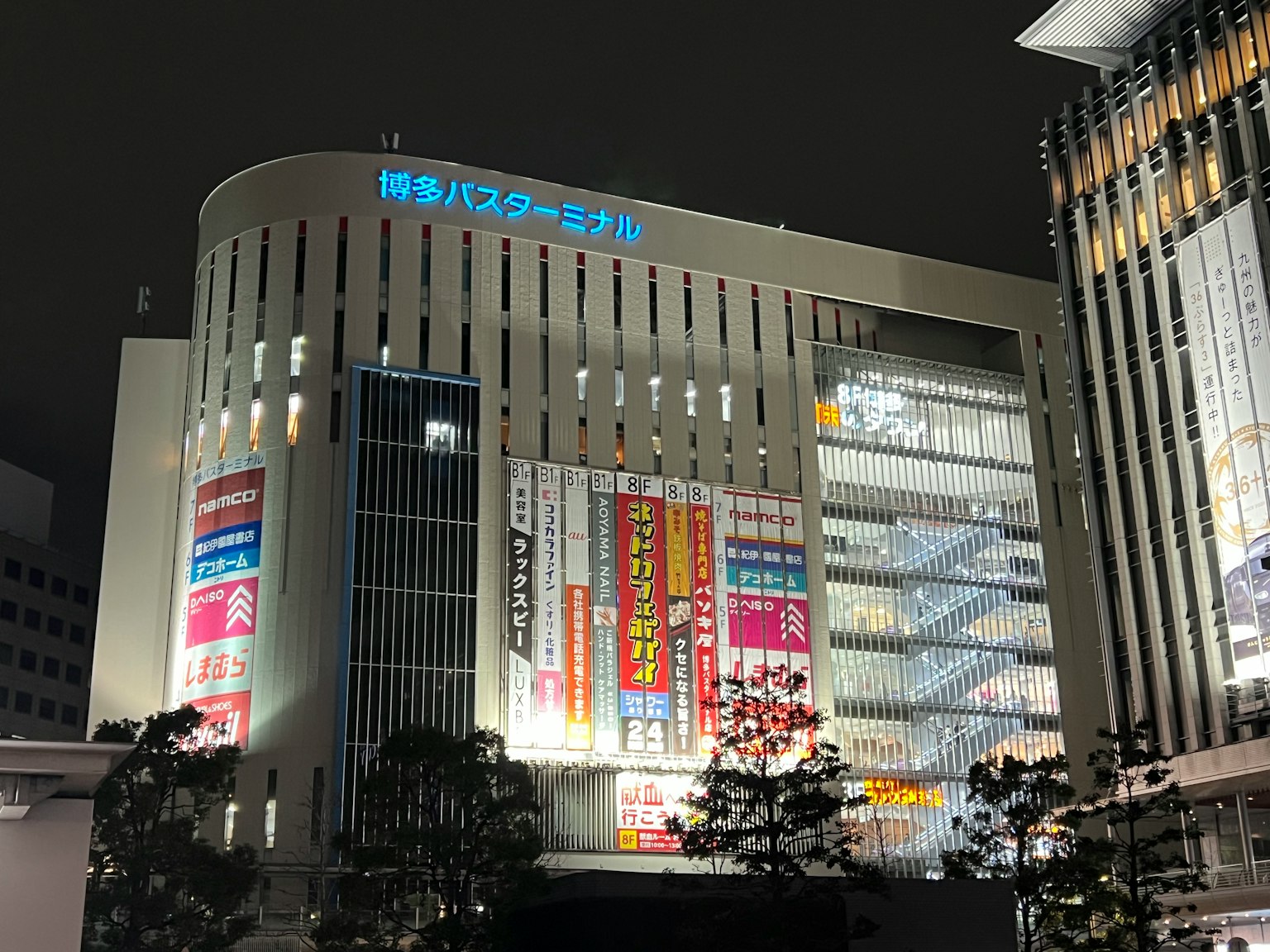 博多车站建筑的夜景，明亮的招牌和现代建筑