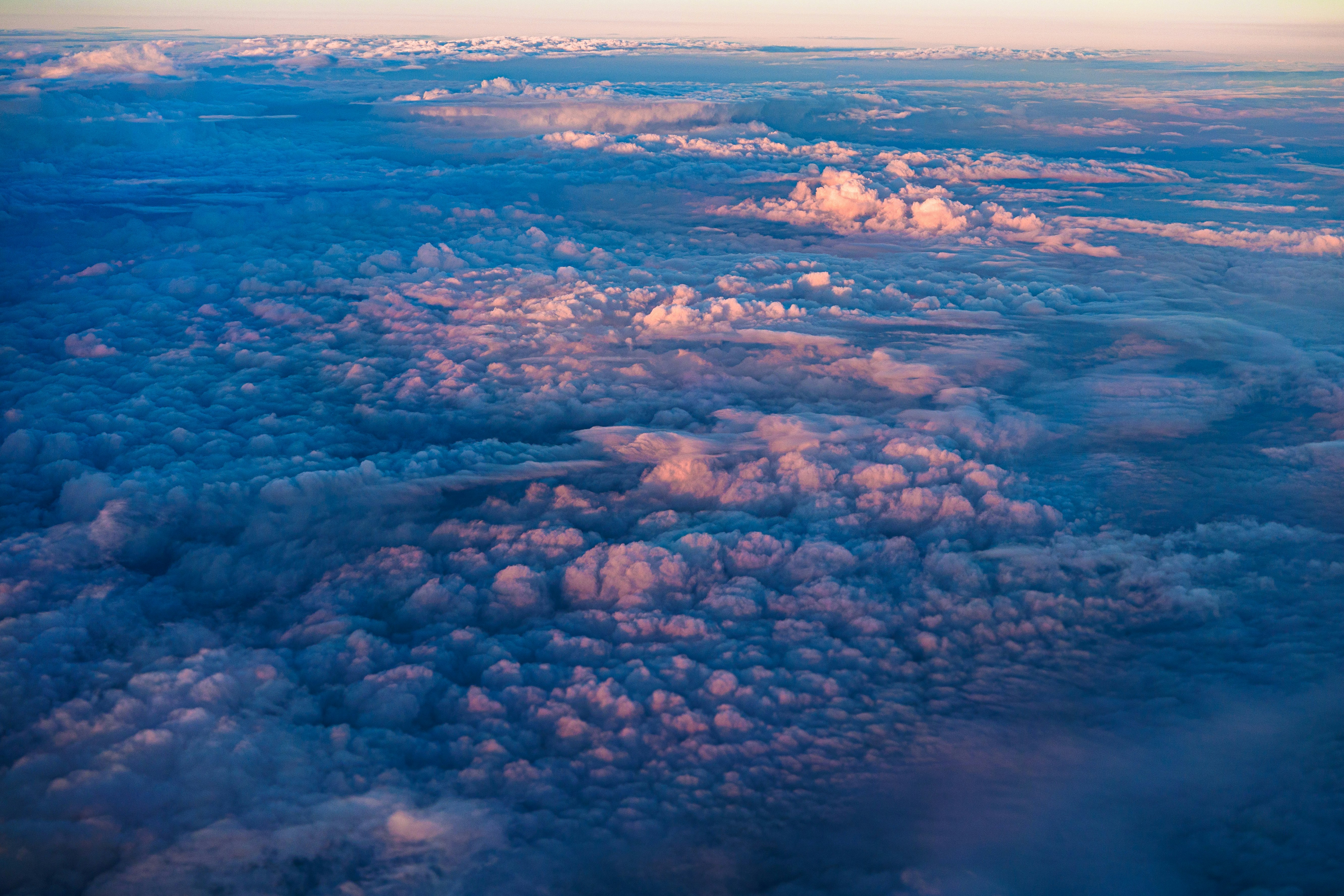 飛行機の窓から見下ろす雲の海と雨雲の広がる空