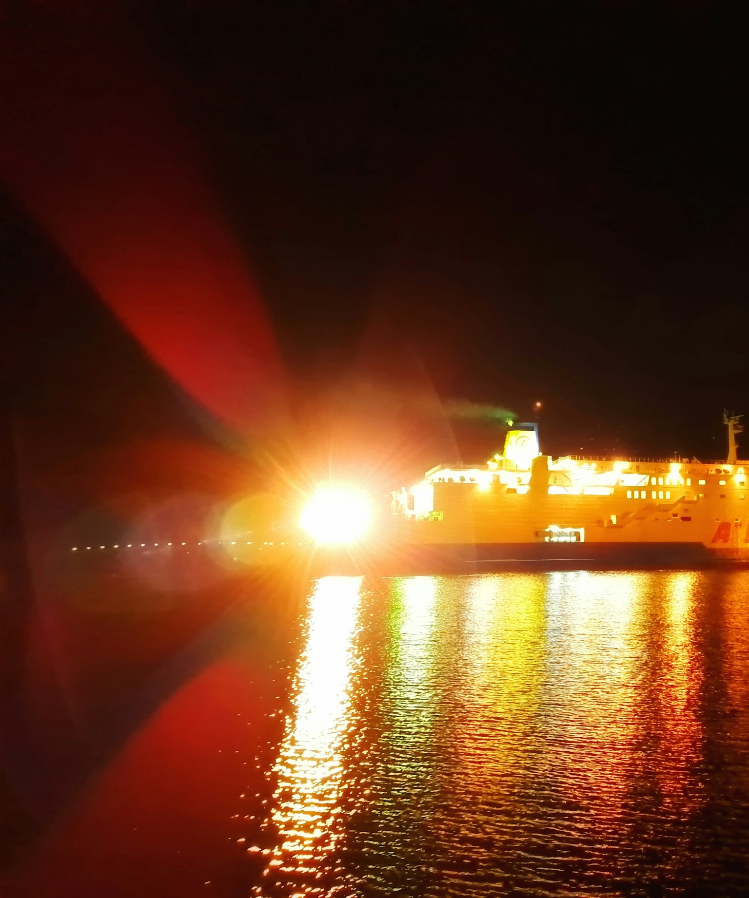 Un barco brillante iluminando el mar nocturno con reflejos