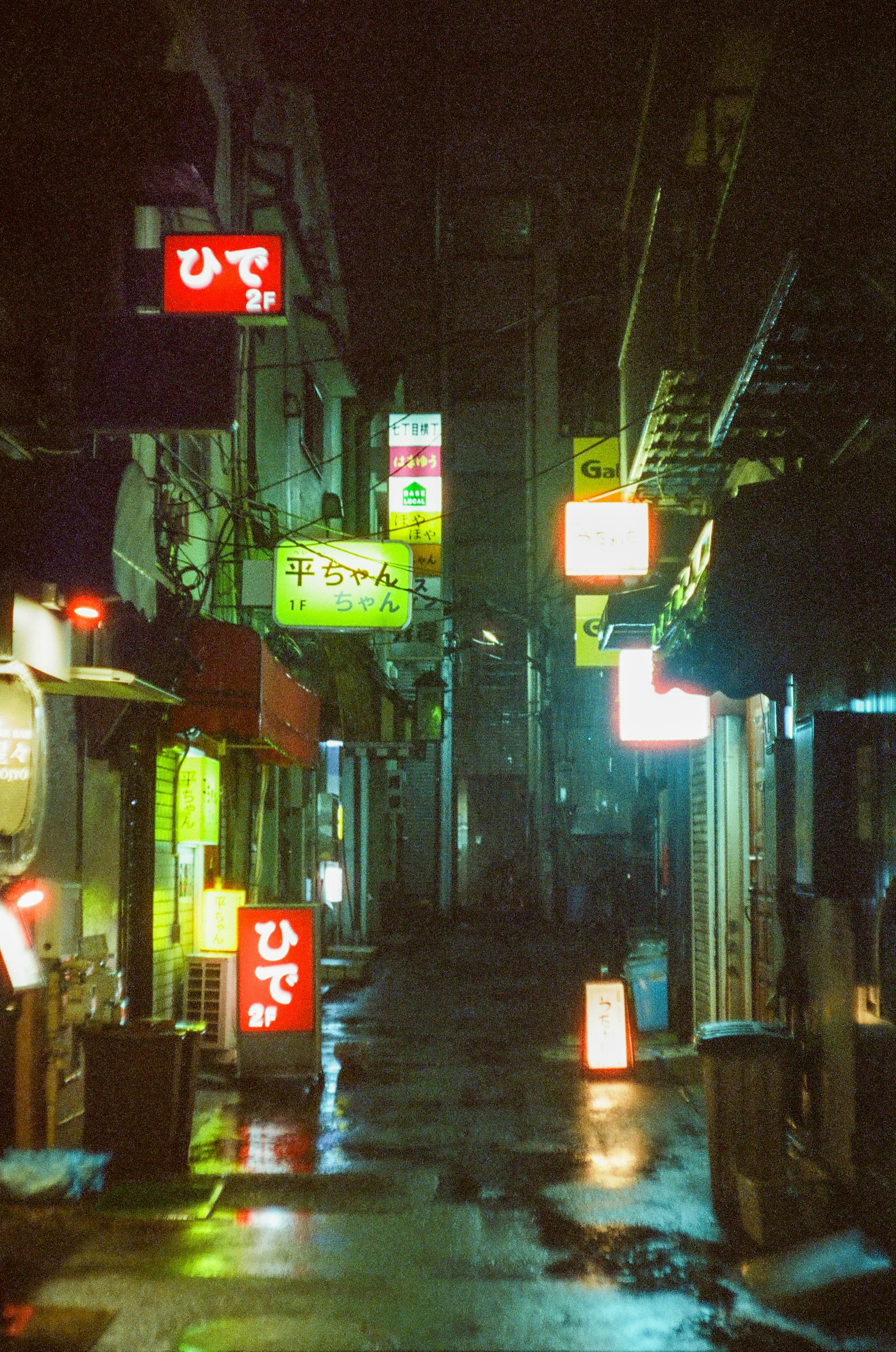 雨の路地に並ぶ飲み屋の看板