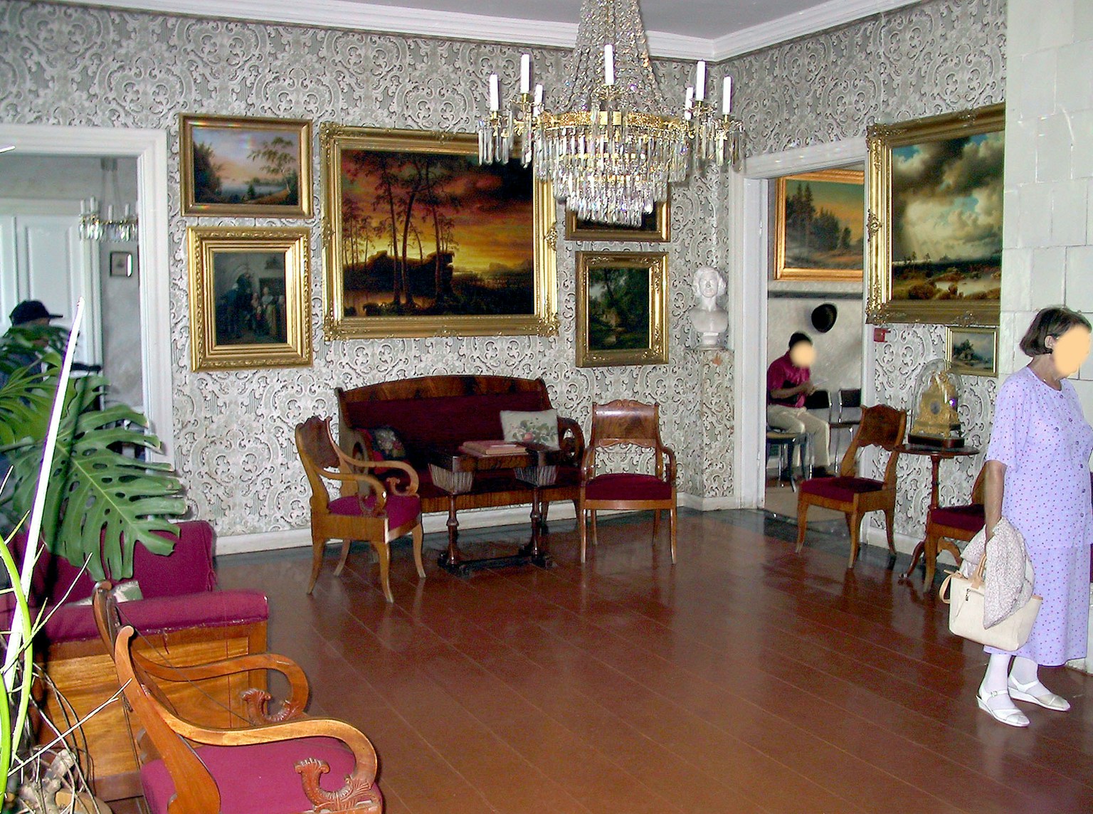 Interior ruang tamu yang elegan dengan lampu gantung dan lukisan berbingkai