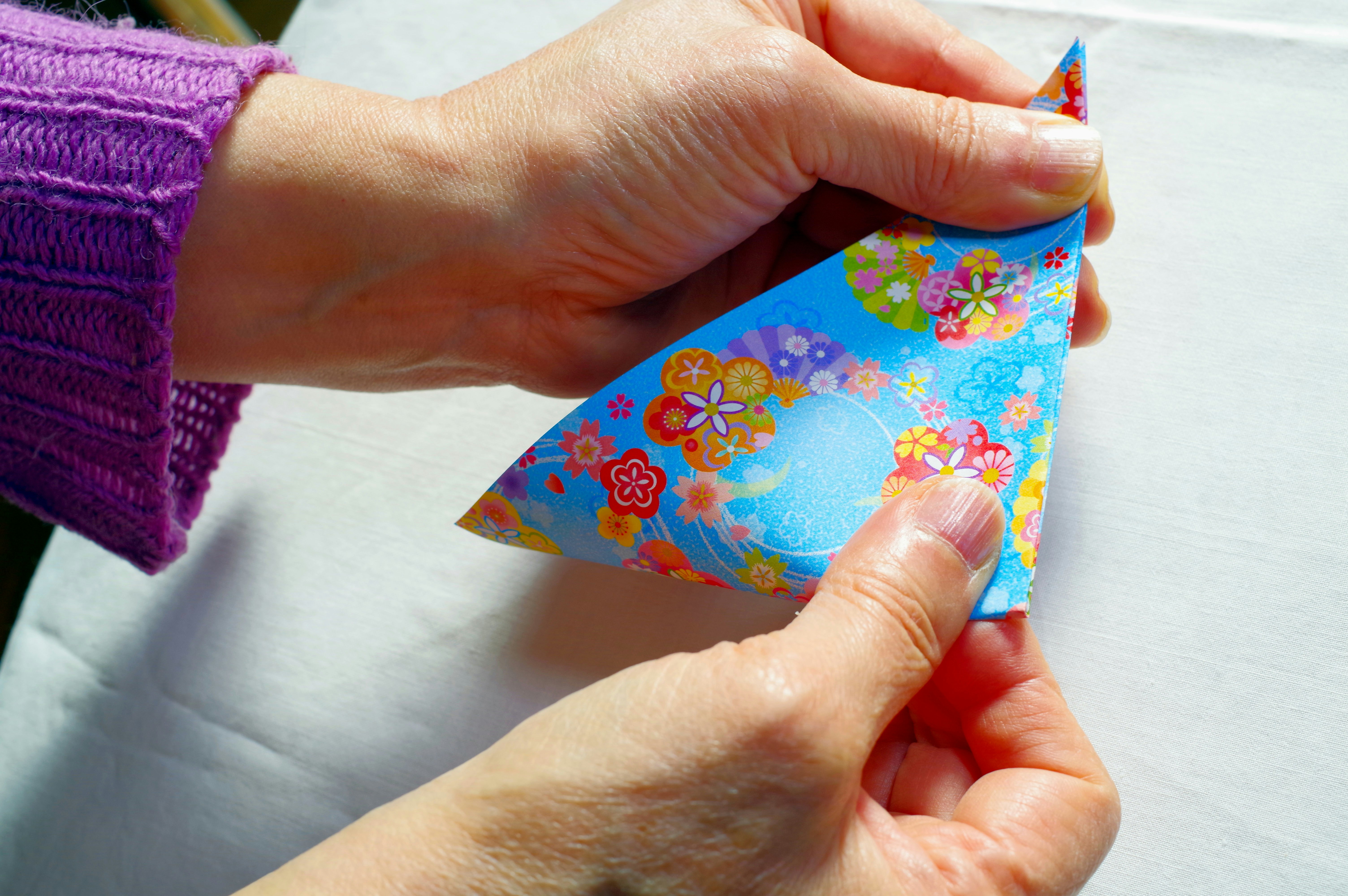 mains en train de plier un origami floral coloré