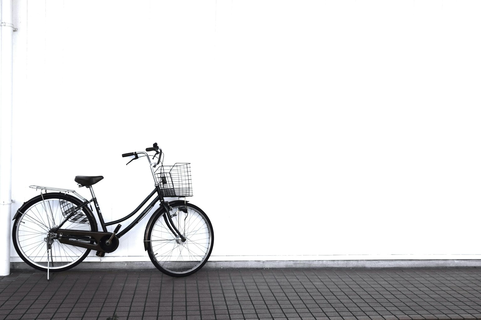 Bicicletta nera appoggiata a un muro bianco