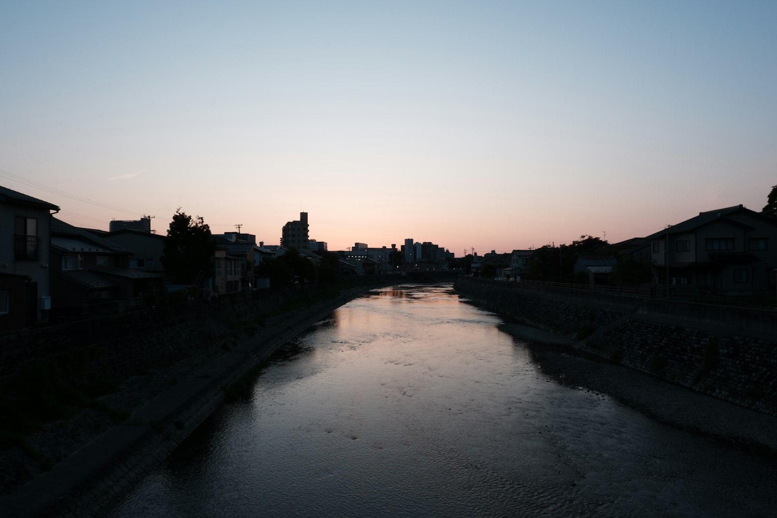 Ruhige Landschaft mit einem Fluss und Silhouetten bei Sonnenuntergang