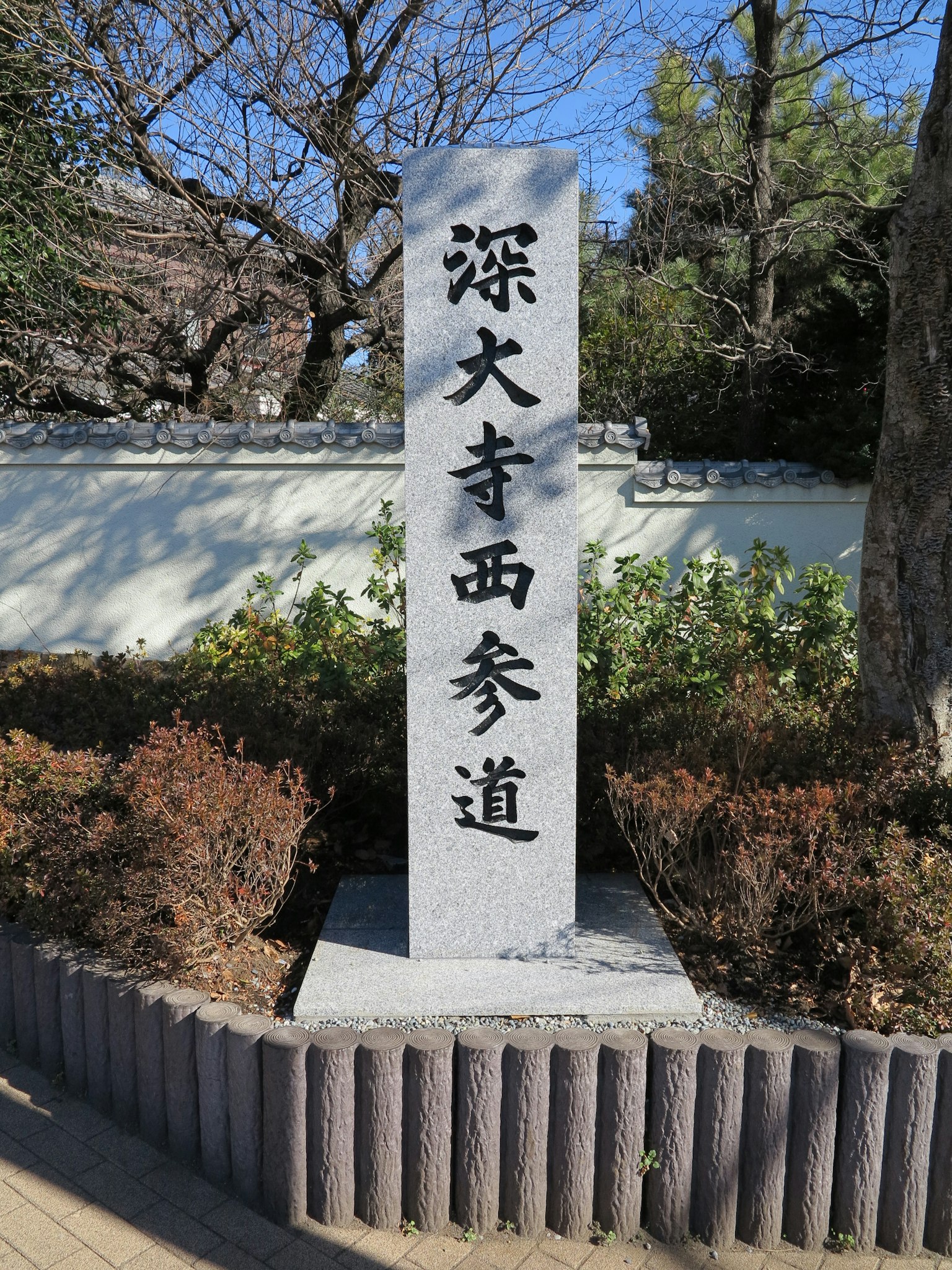 Monumen batu dari Jalan Masuk Barat Jindaiji dikelilingi oleh pepohonan