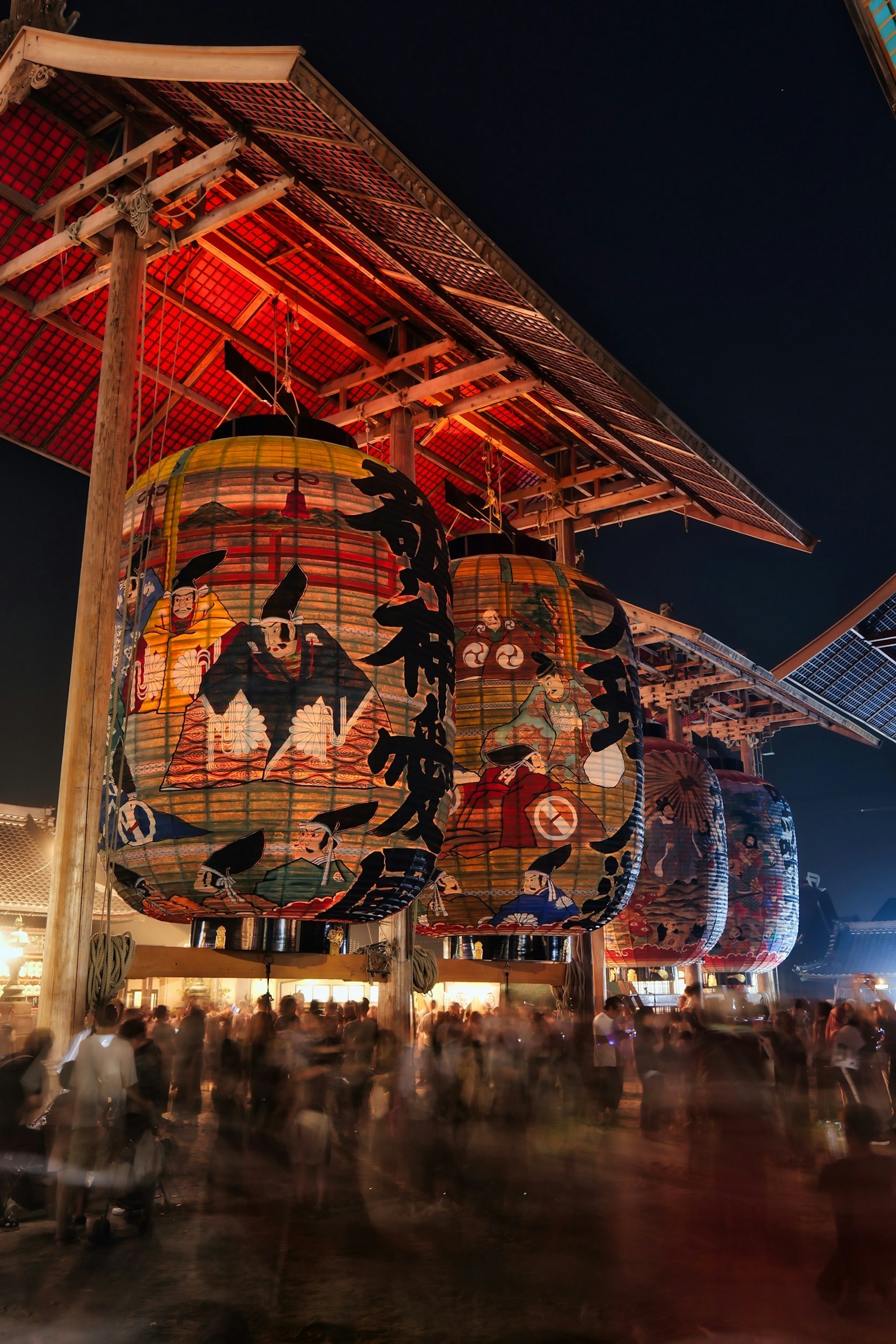 Colorful lanterns hanging at a night festival with a lively crowd