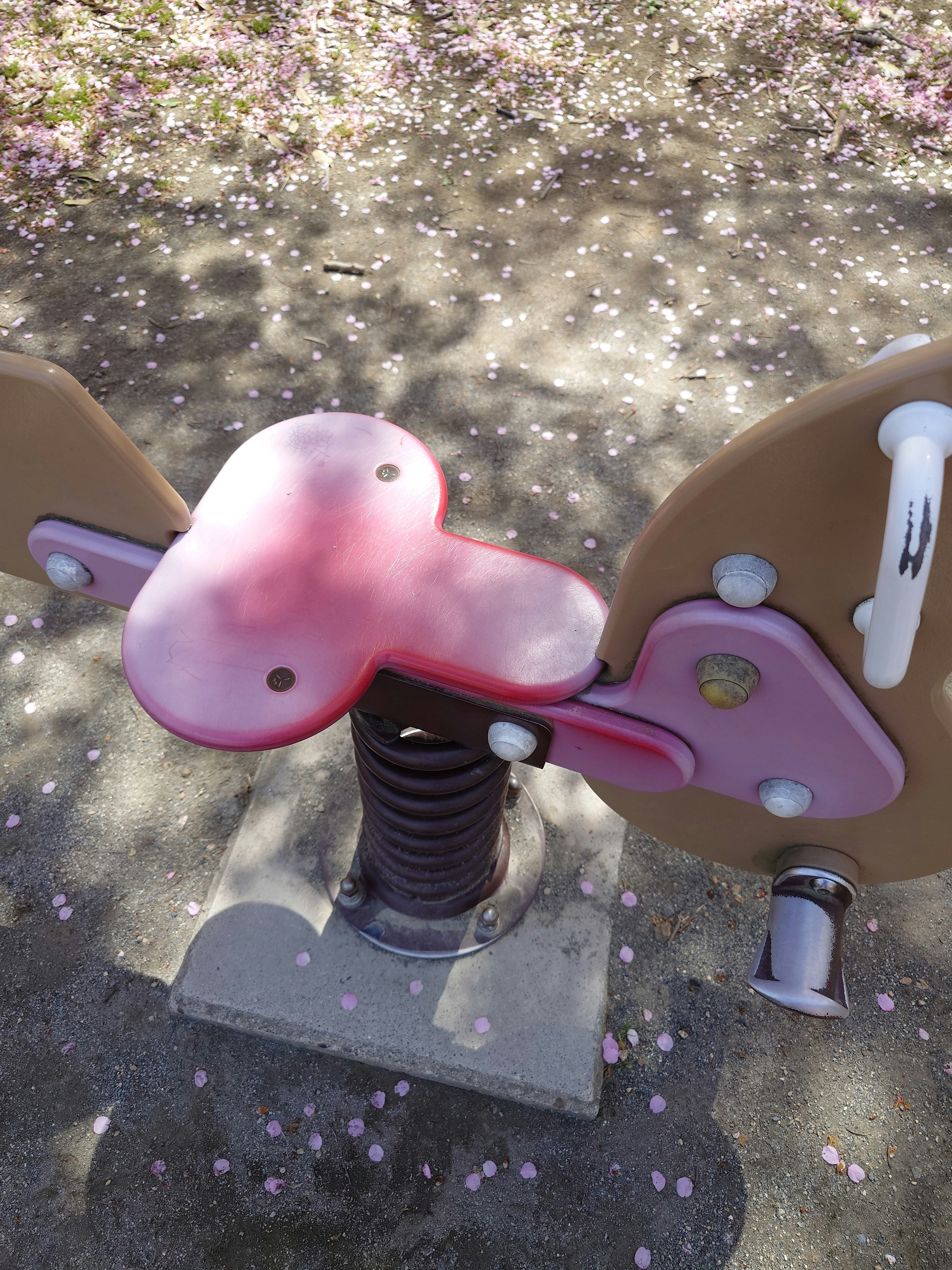 公園の遊具に乗るピンクのスプリングバイクのある遊び場