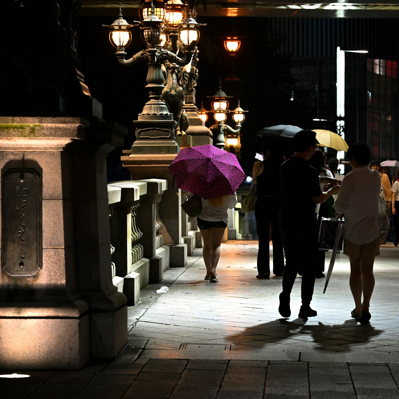 People walking with umbrellas in a city at night