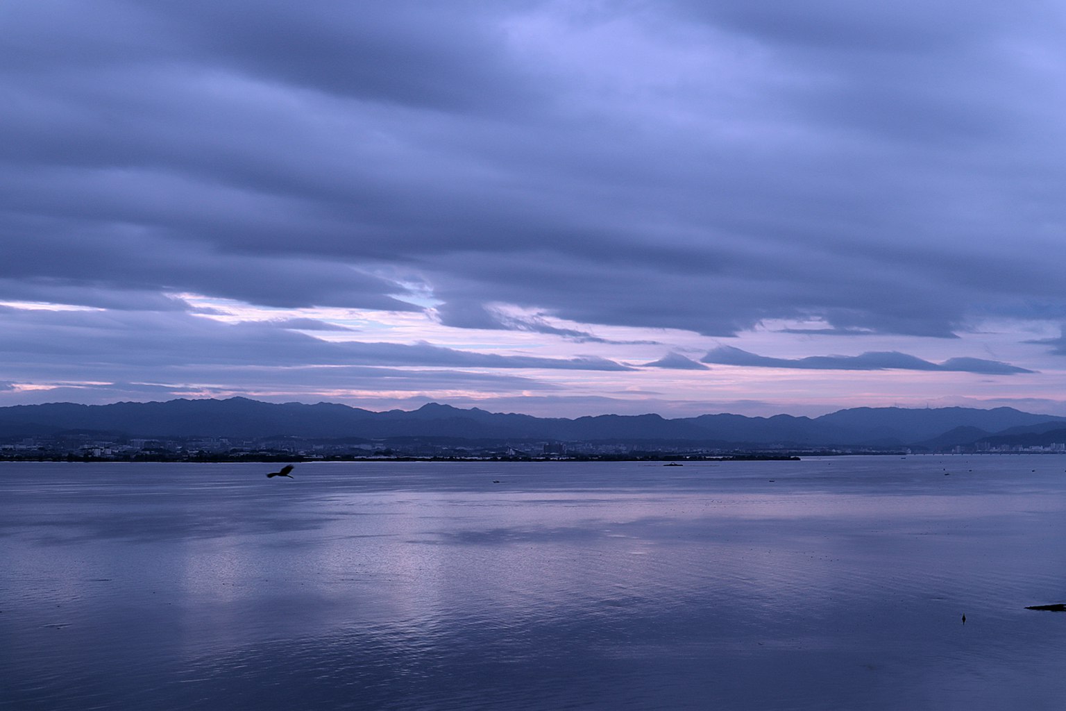Paysage serein reflétant un ciel bleu-violet pâle sur des eaux calmes