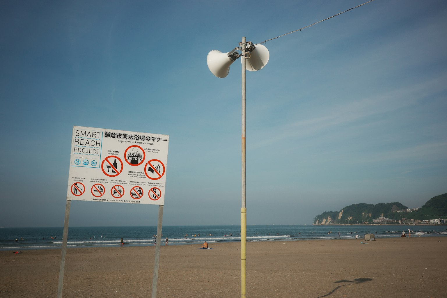 Strandszene mit Warnschild und Lautsprechern