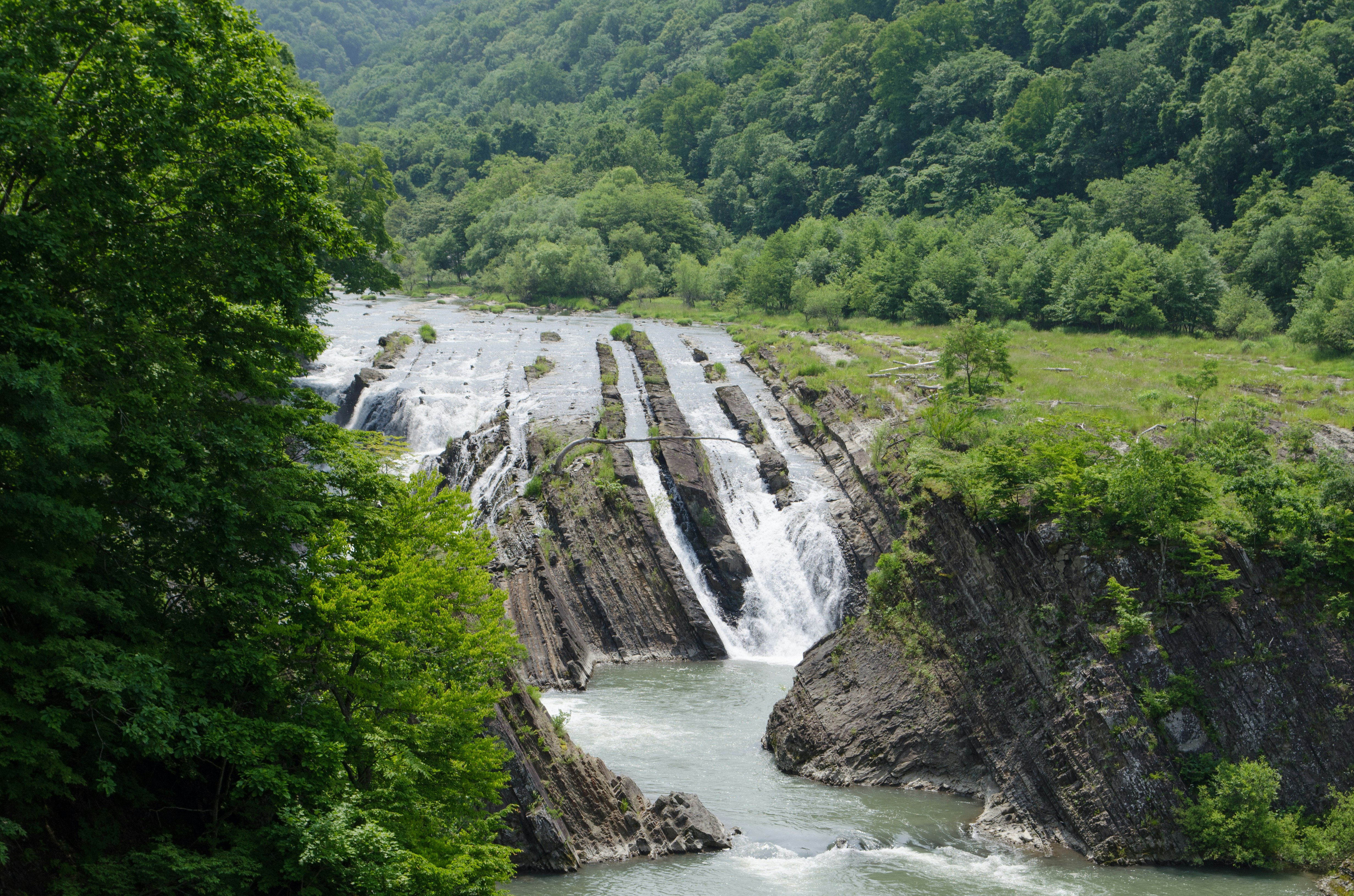 cascada y río fluyendo por un valle verde