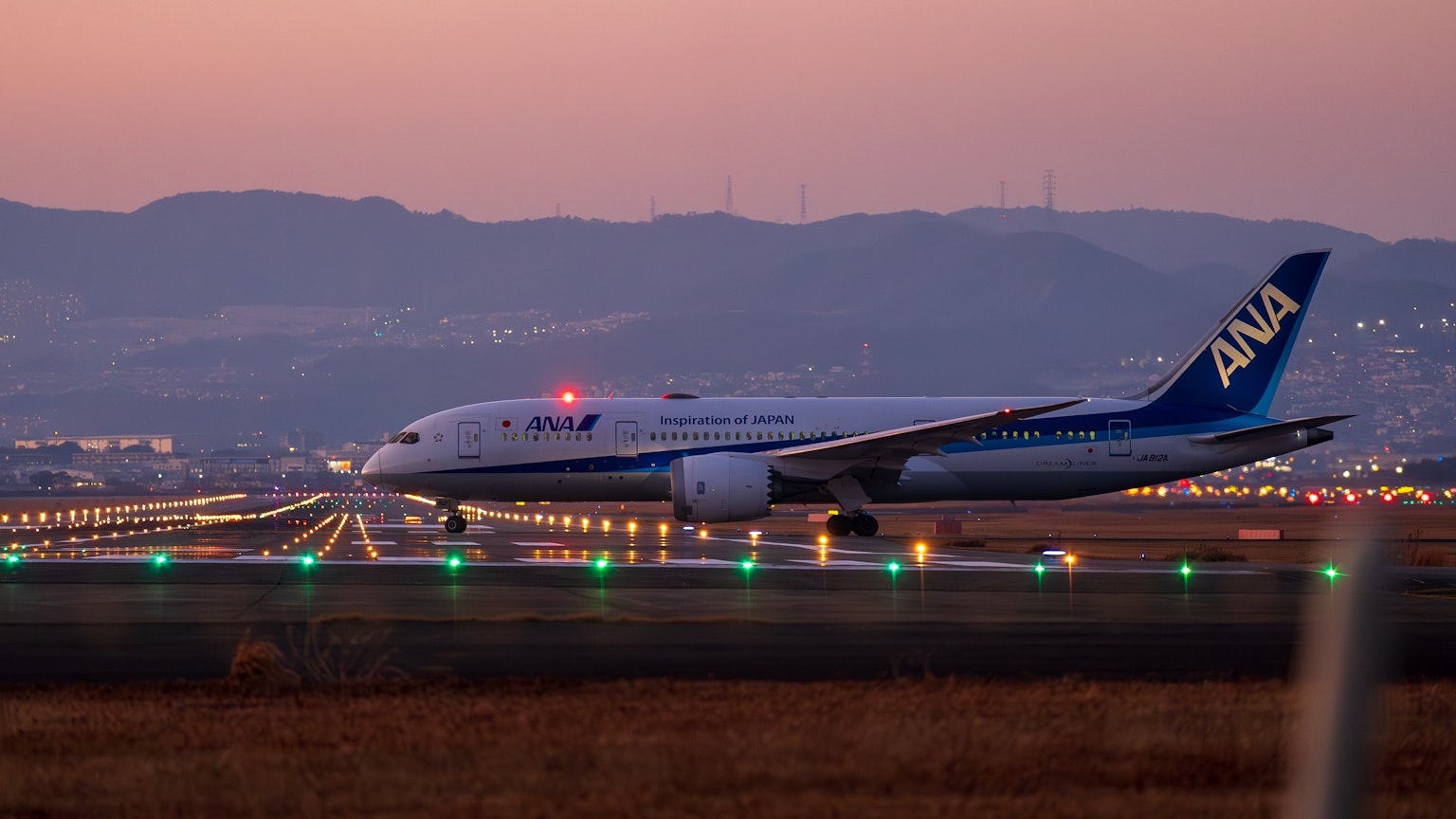 ANA-Passagierflugzeug rollt bei Sonnenuntergang über die Landebahn