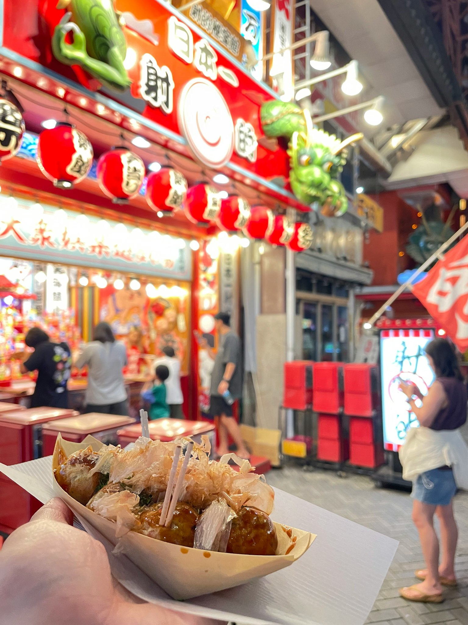 手持美味炸食物在夜市的熱鬧小攤前