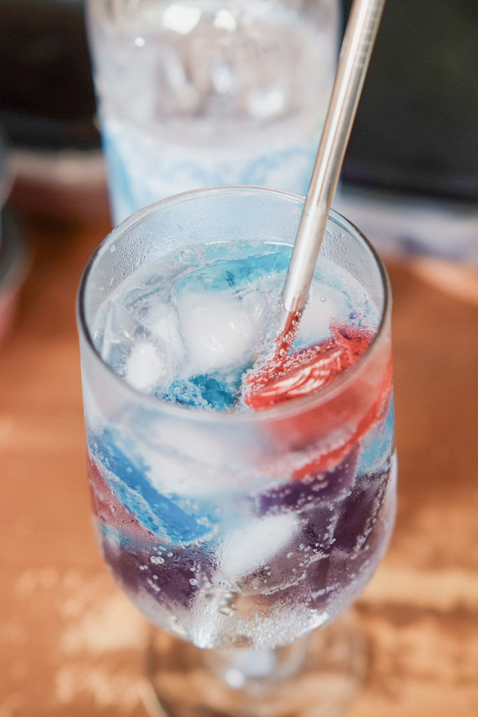 Gelas transparan dengan es dan kubus es berwarna-warni dalam minuman