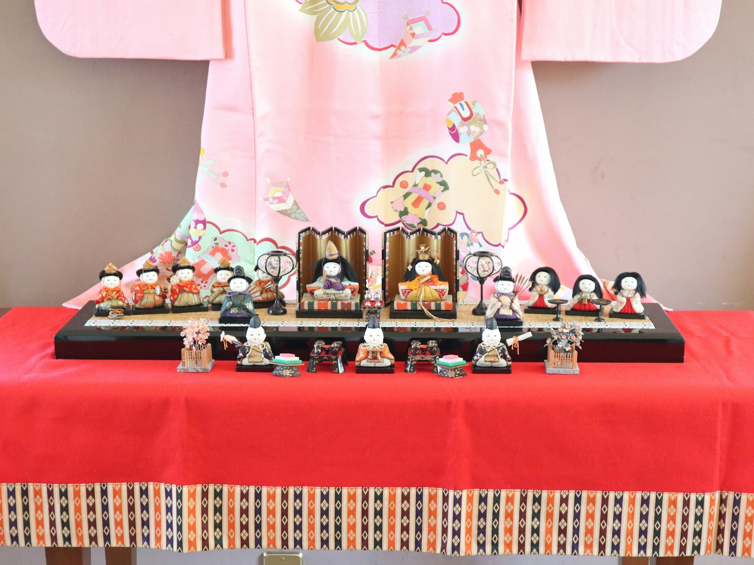 Pameran boneka Hina Matsuri dengan latar belakang kimono merah muda