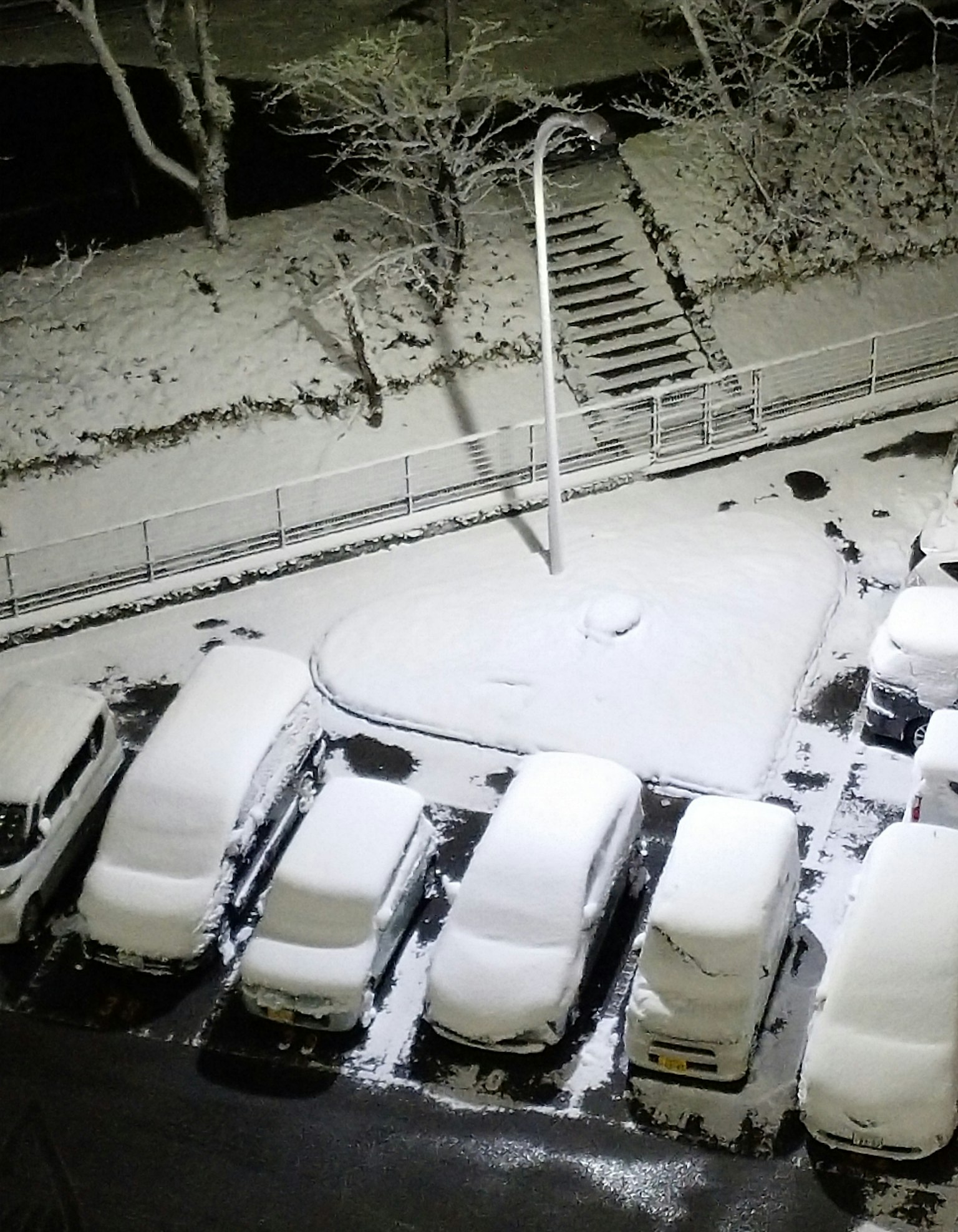 Schneebedeckter Parkplatz mit Autos und Treppen