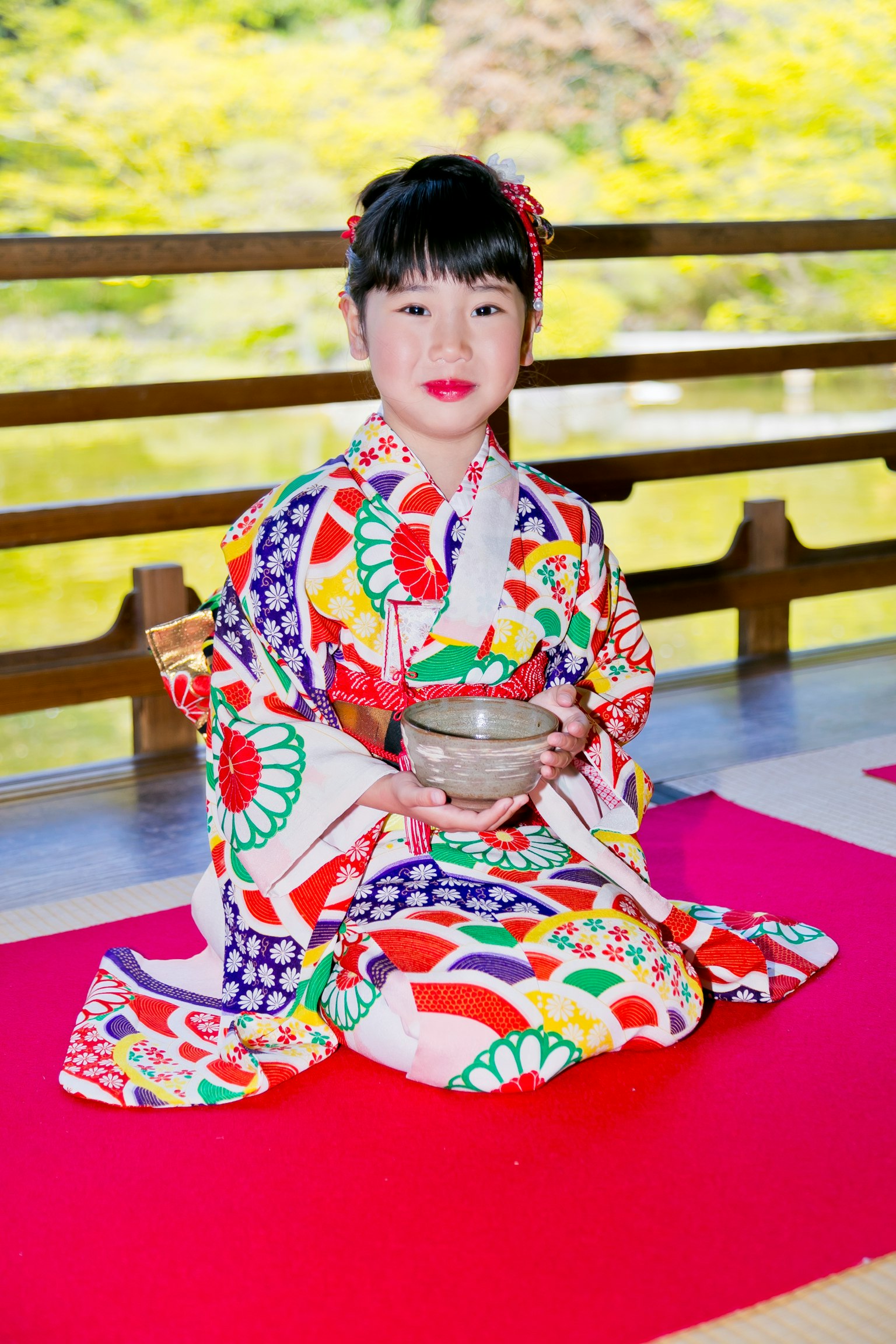 Une fille en kimono coloré tenant un bol à thé en position assise