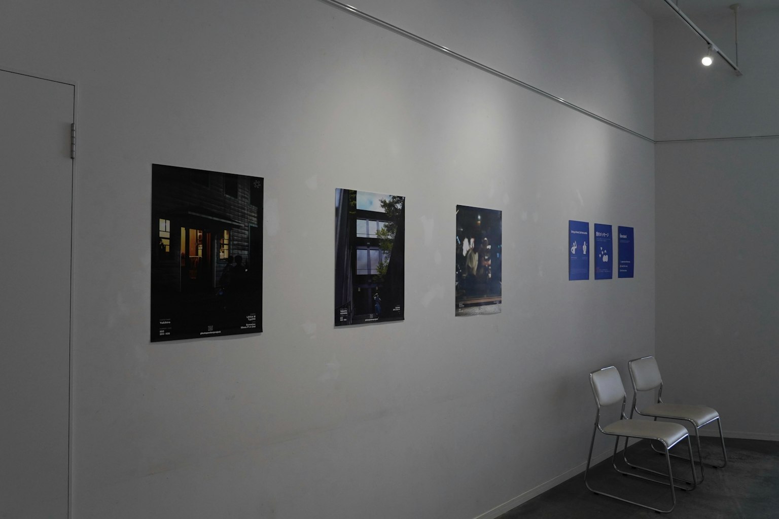 Galería de arte con carteles exhibidos en una pared blanca con varios colores