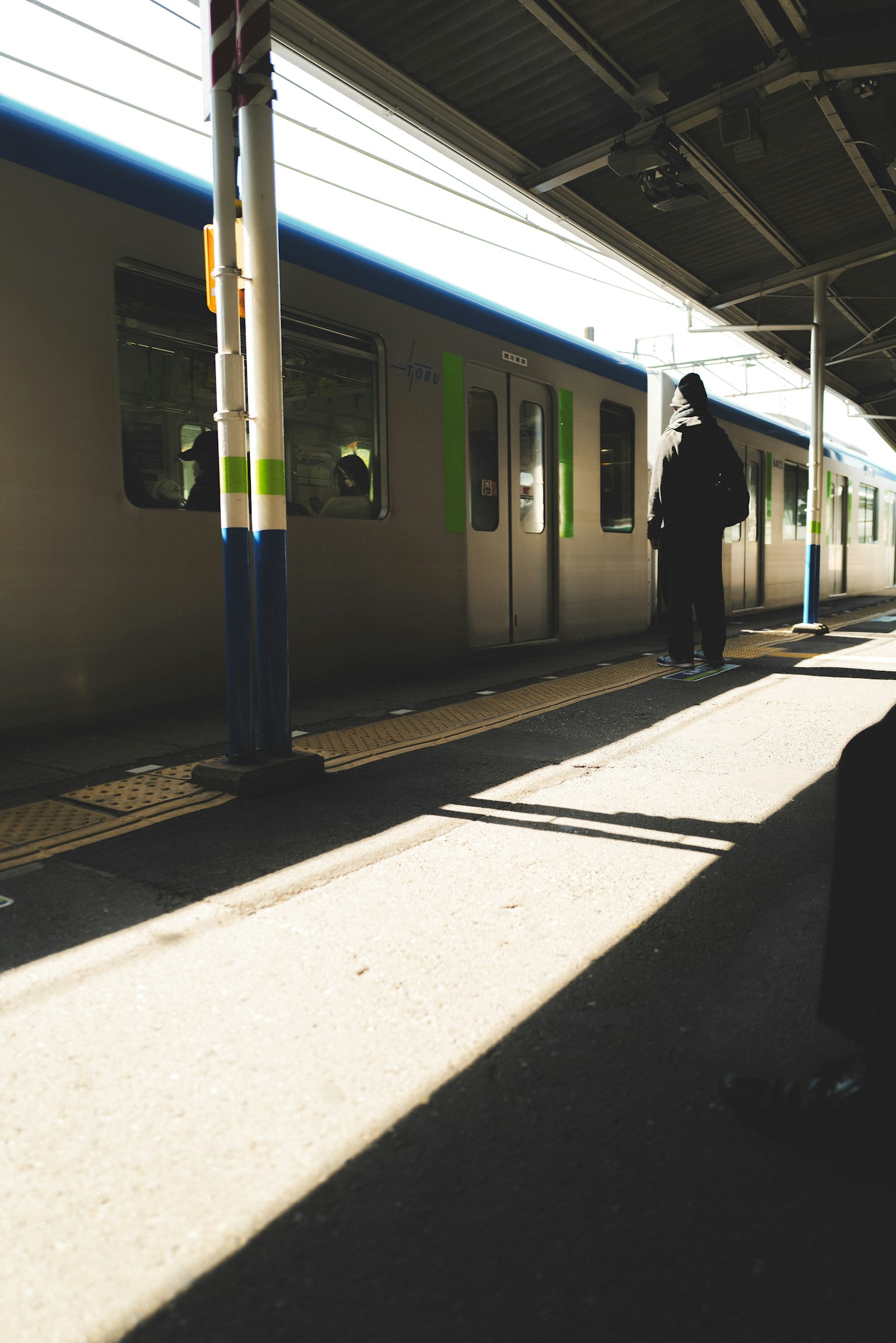 Bayangan seseorang menunggu di stasiun kereta yang tenang dengan cahaya terang
