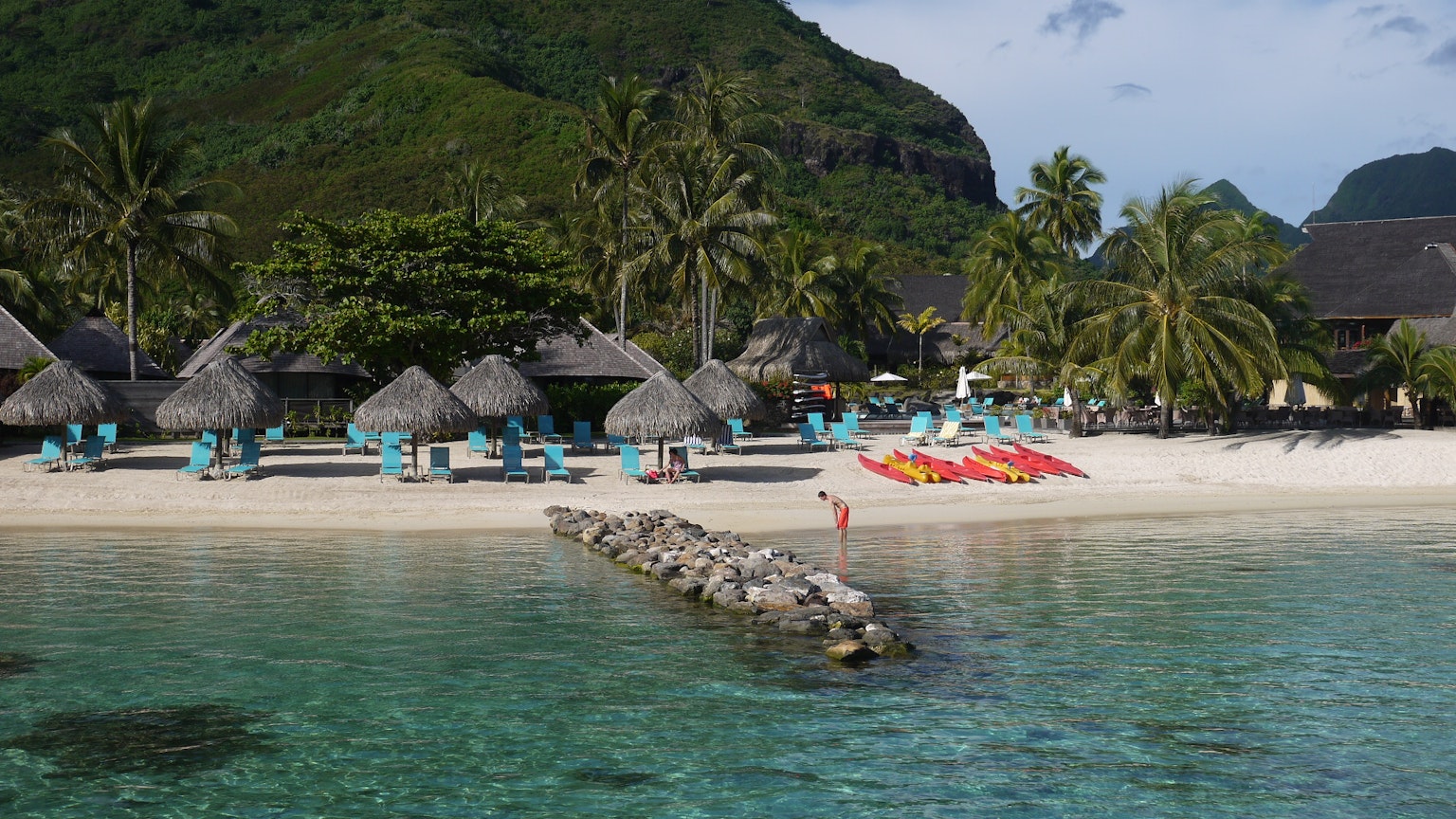 Vista de playa pintoresca con cabañas de resort agua turquesa y palmeras