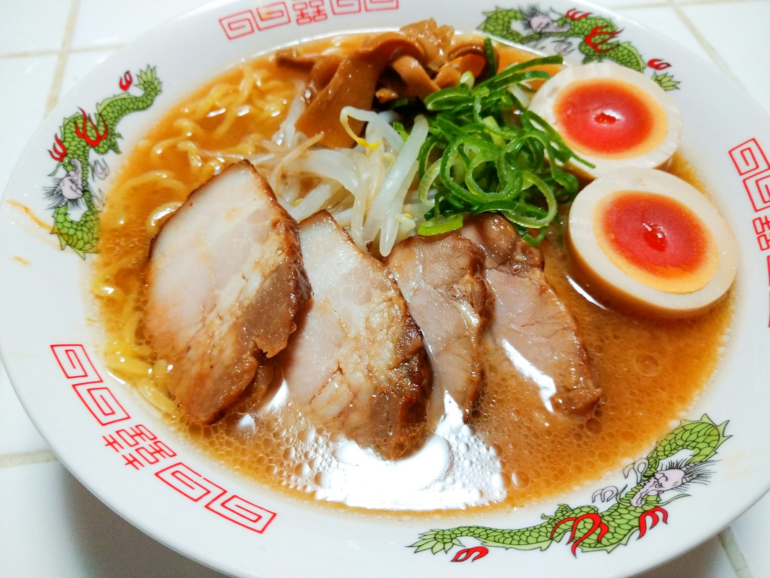 A bowl of ramen topped with slices of pork and soft-boiled eggs