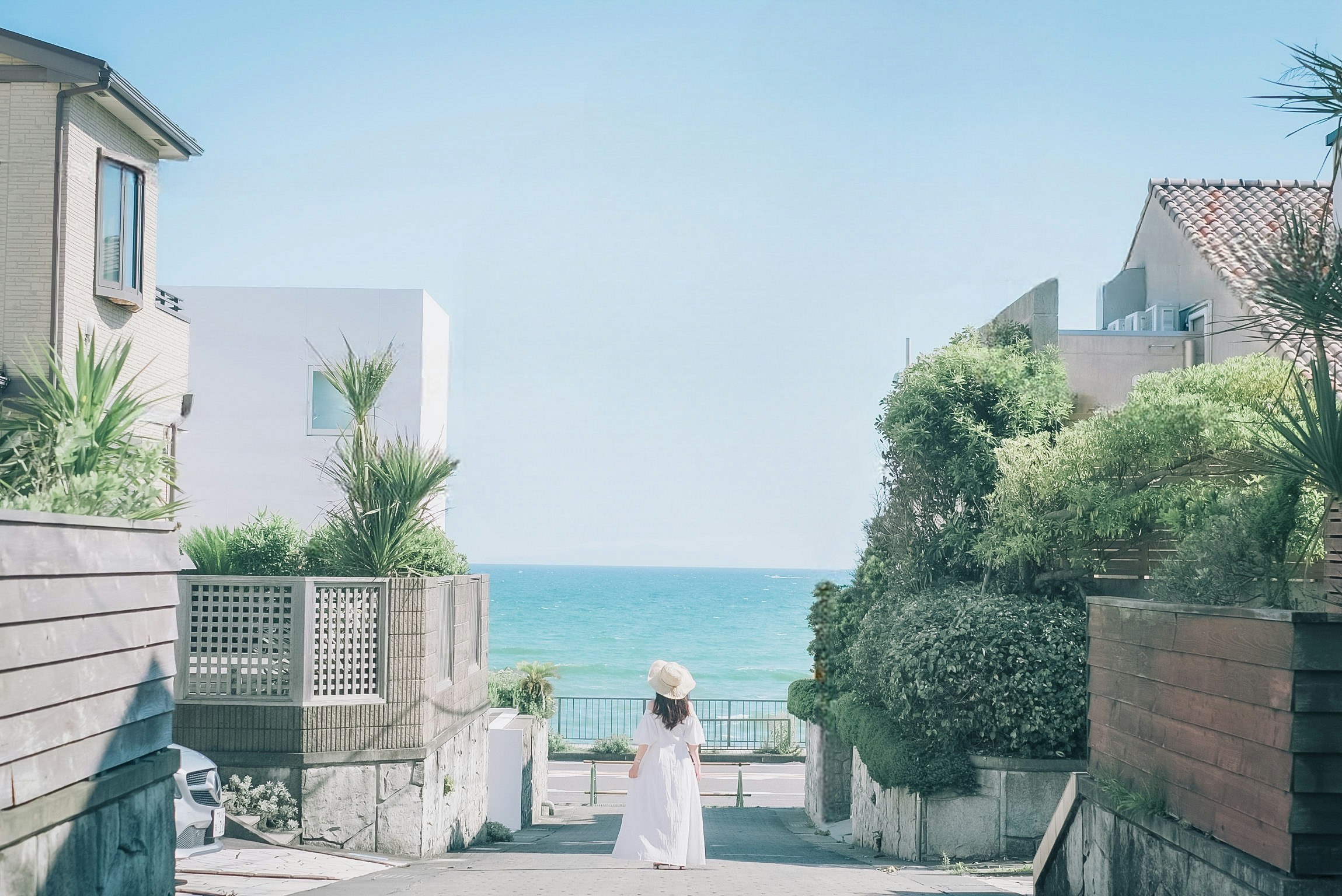 Un chemin en bord de mer avec vue sur l’océan bleu et des bâtiments blancs