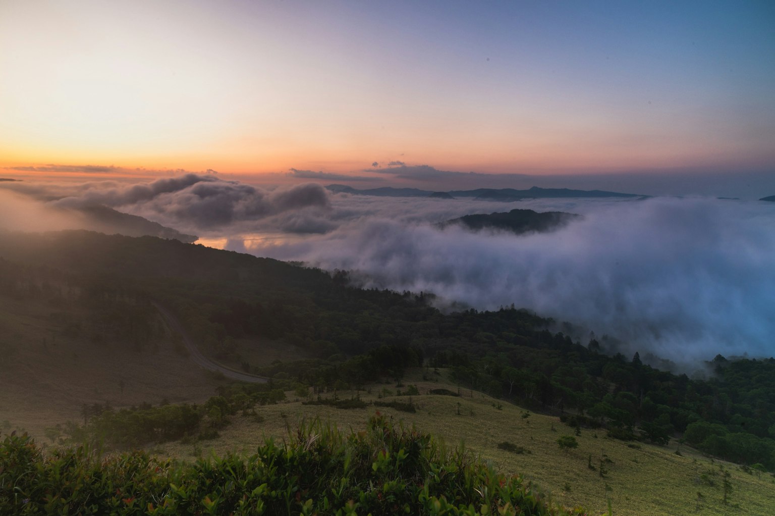 Beeindruckende Landschaft von Bergen, die im Nebel bei Sonnenaufgang gehüllt sind