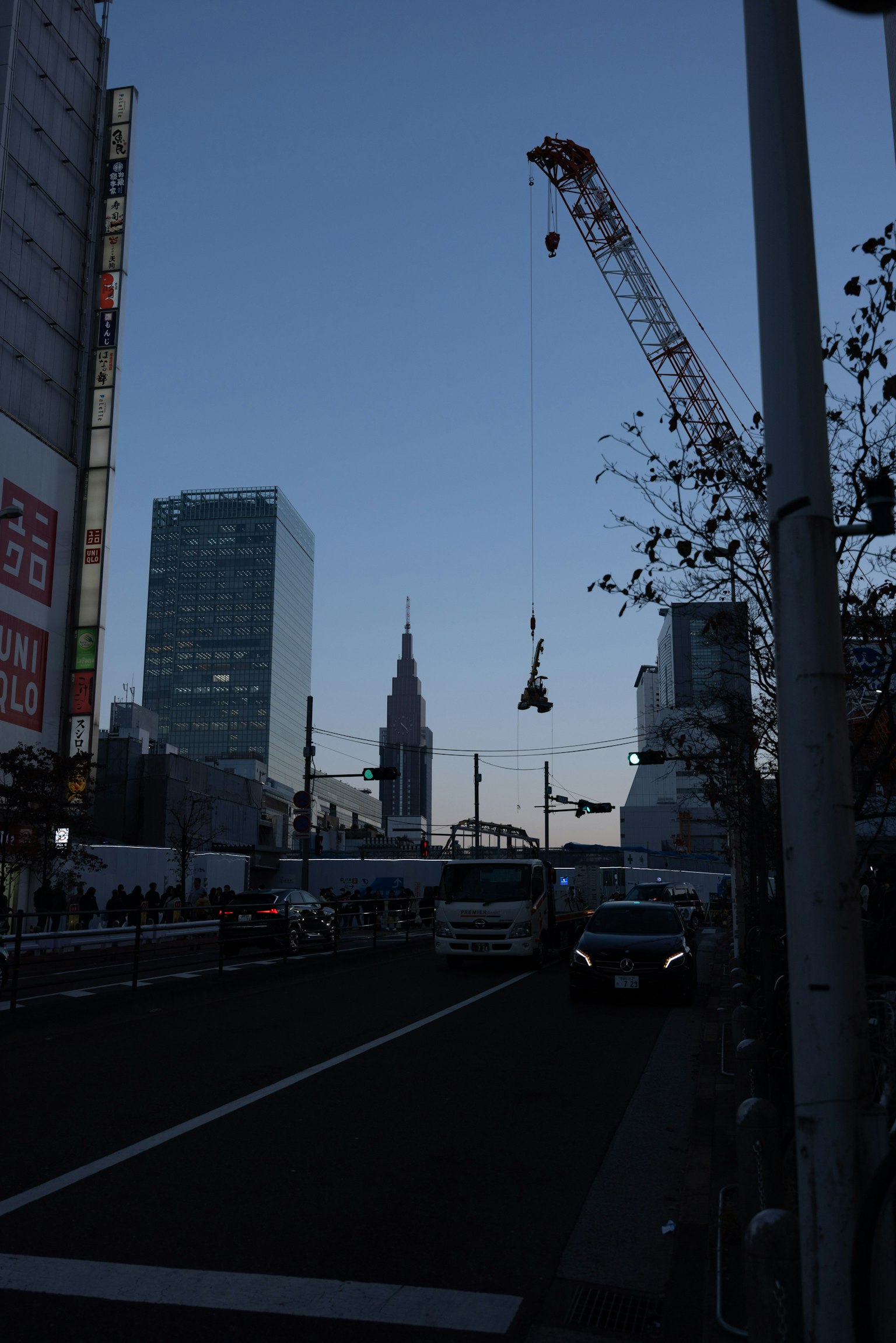 ภาพเงาของเส้นขอบฟ้าของชินจูกุในยามพลบค่ำพร้อมกับเครนที่กำลังทำงานก่อสร้าง