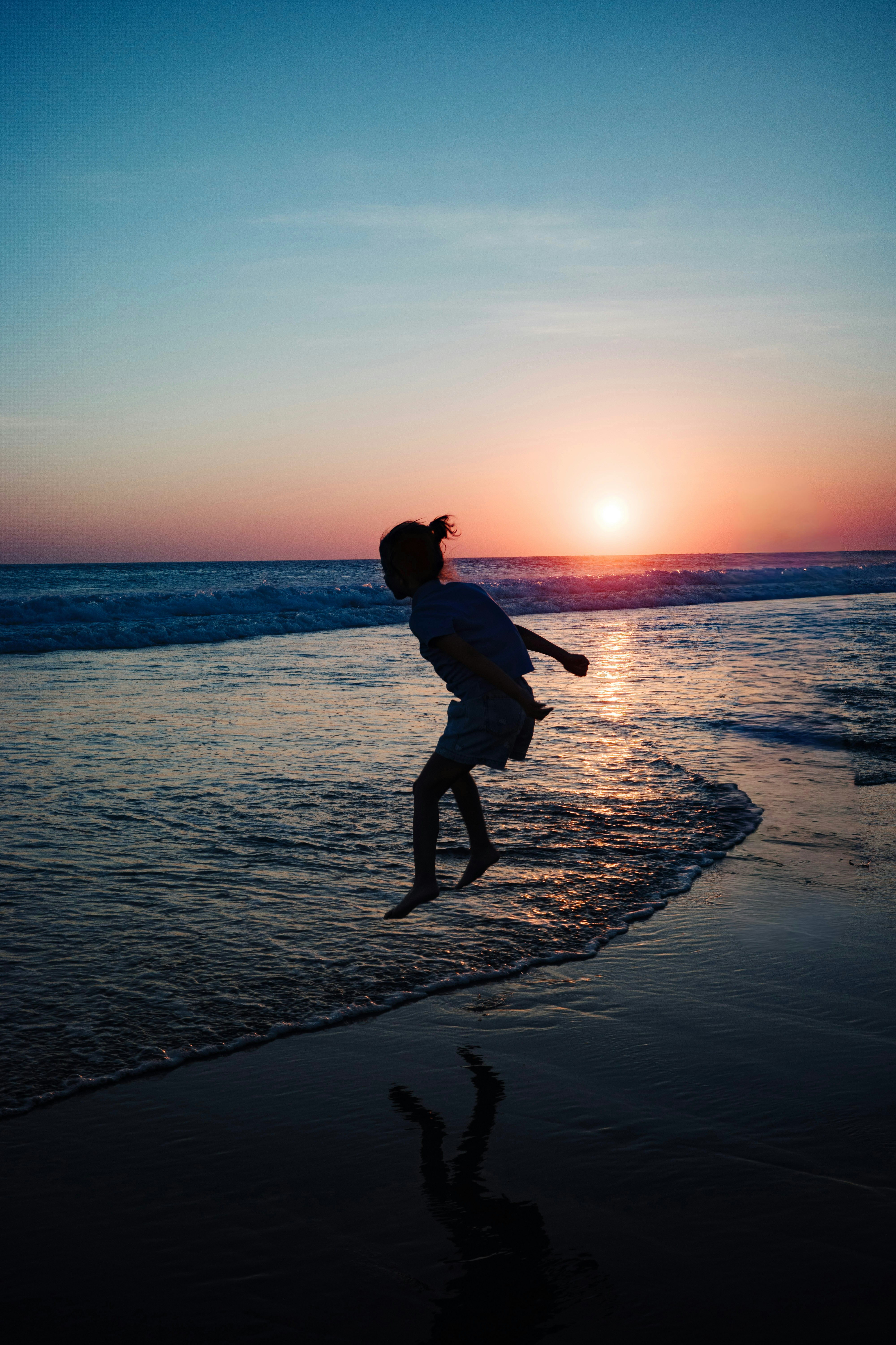 a person running along the beach at sunset