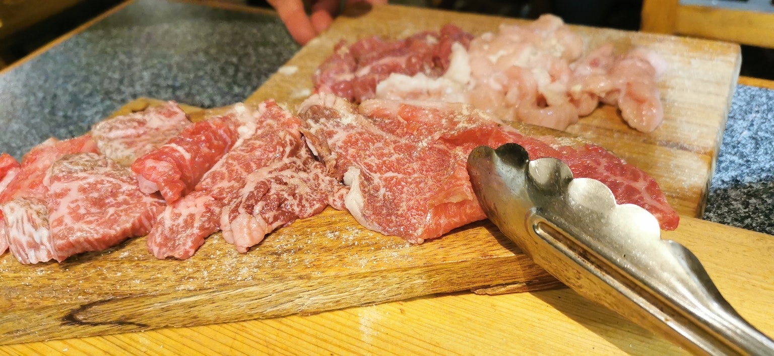 Assortiment de viandes sur une planche à découper en bois avec des pinces à côté