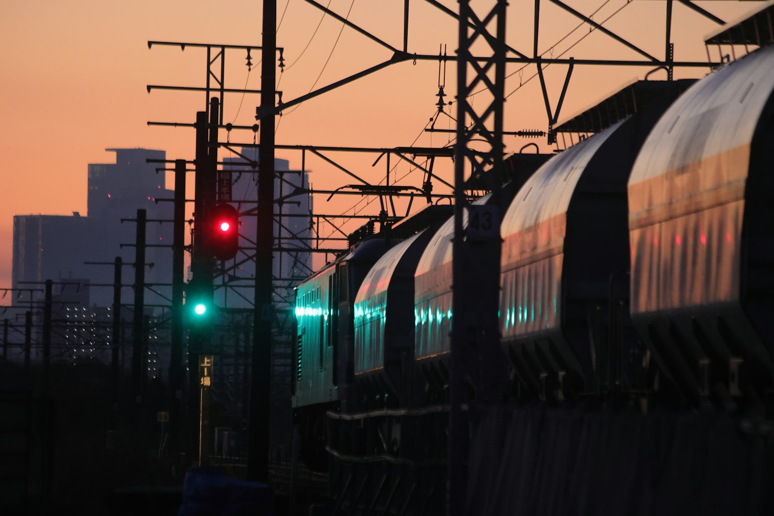 Zug, der unter einem grünen Signal bei Sonnenuntergang fährt