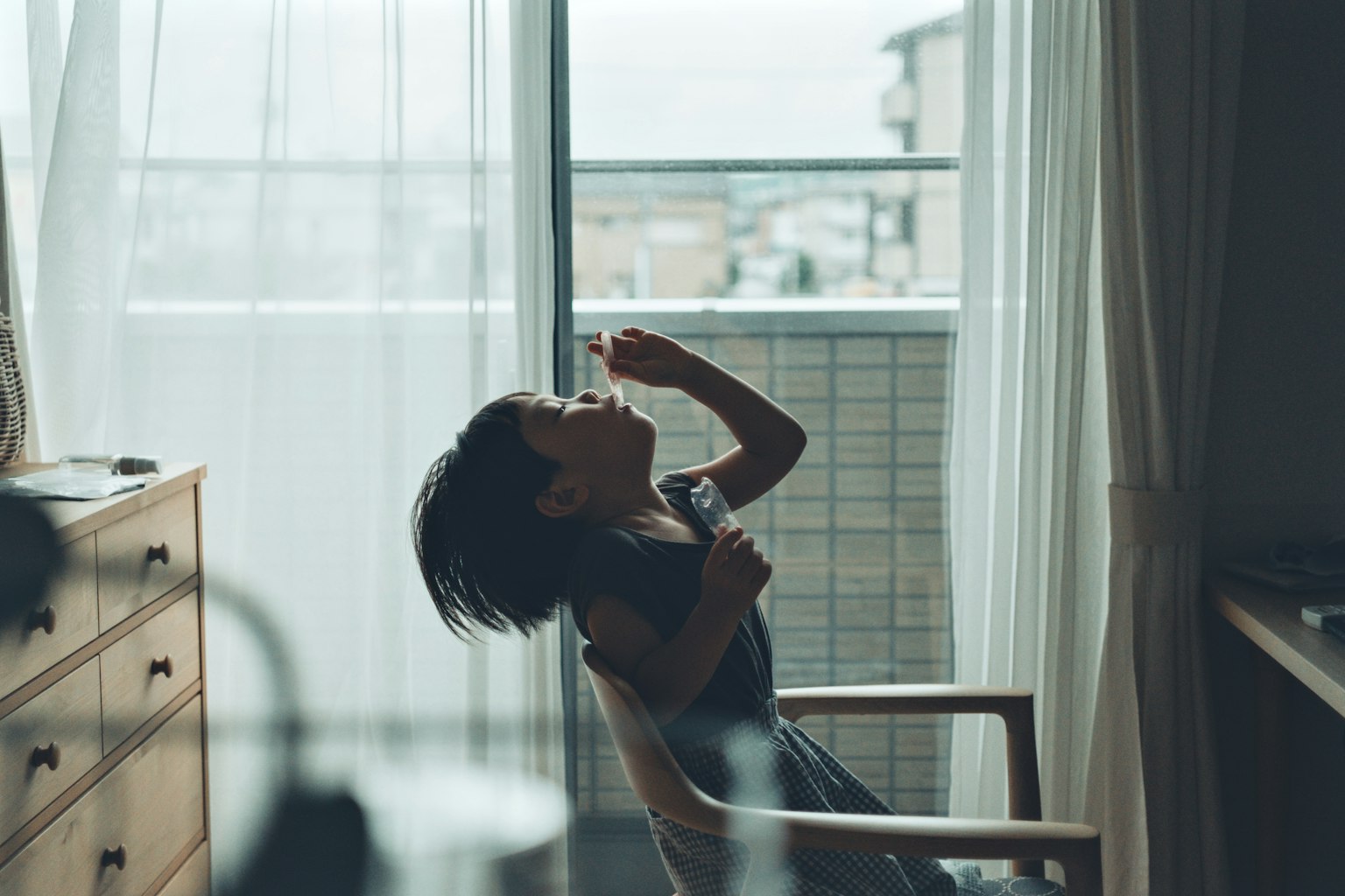 창가에서 머리를 흔드는 아이의 실루엣이 보이는 방 안