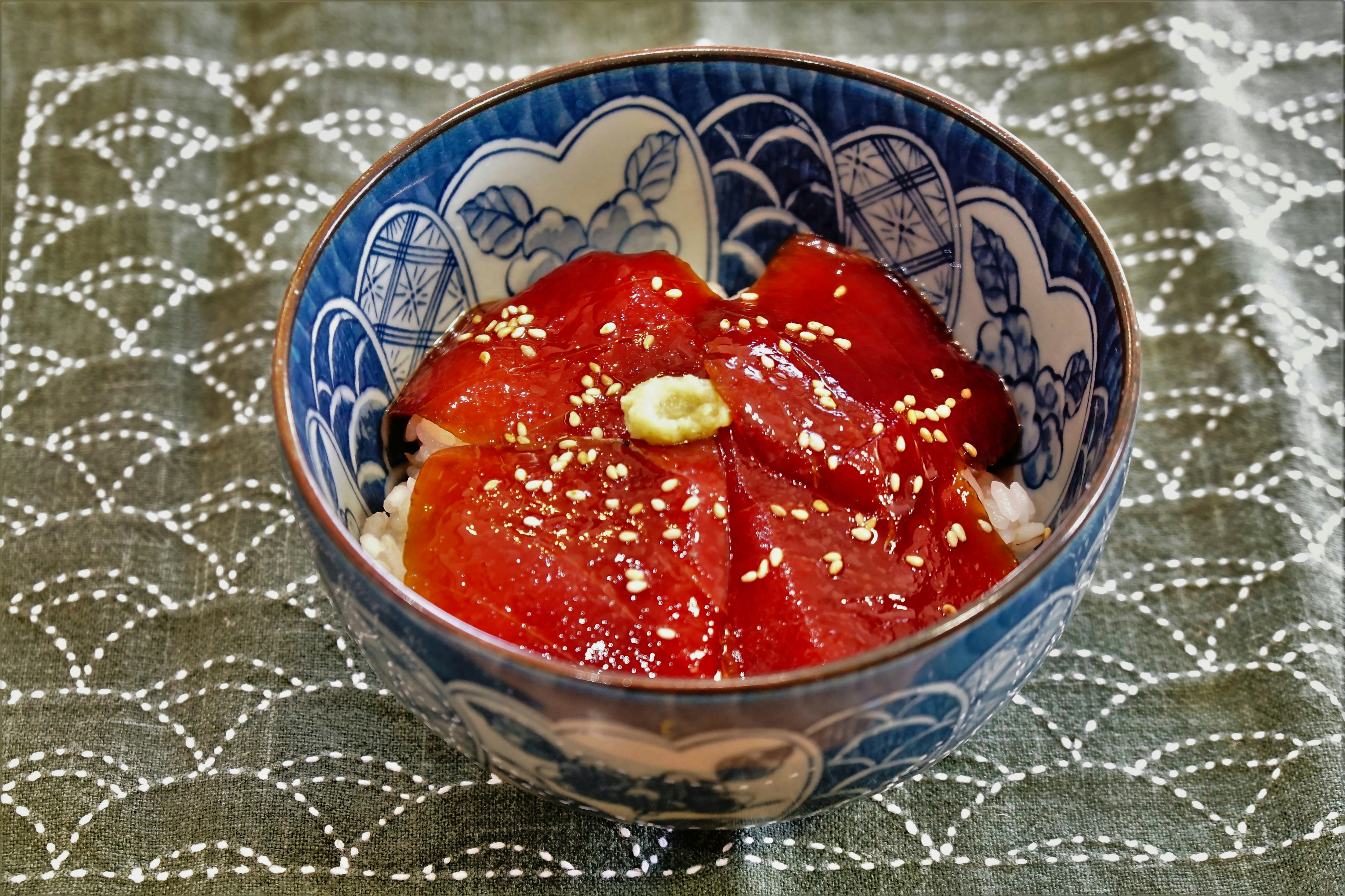 一个装有红色生鱼片的美丽蓝色日本碗，上面撒有芝麻