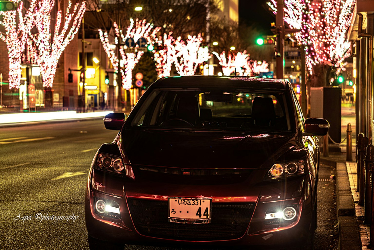 Voiture noire avec des arbres illuminés dans une rue de ville nocturne