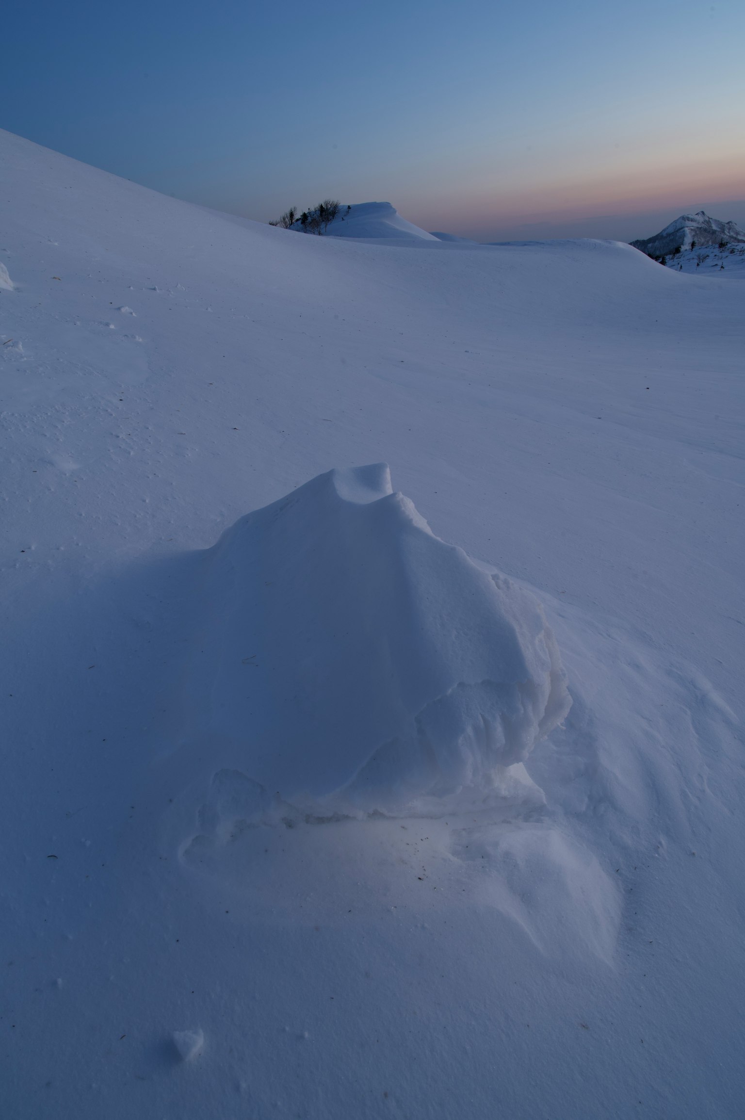 Monticule de neige recouvert ressemblant à une petite colline avec ciel crépusculaire