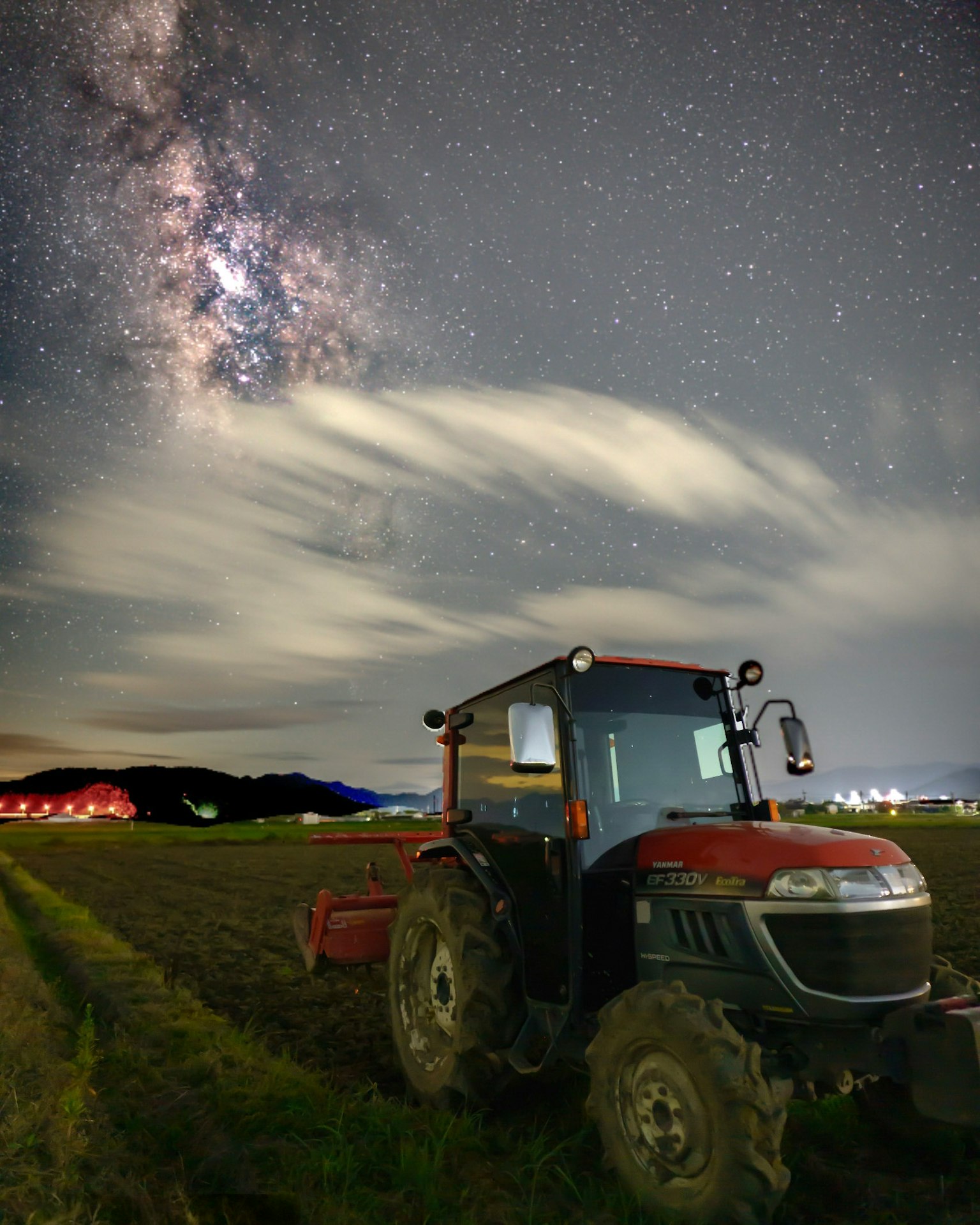 Tractor en un campo bajo un cielo estrellado