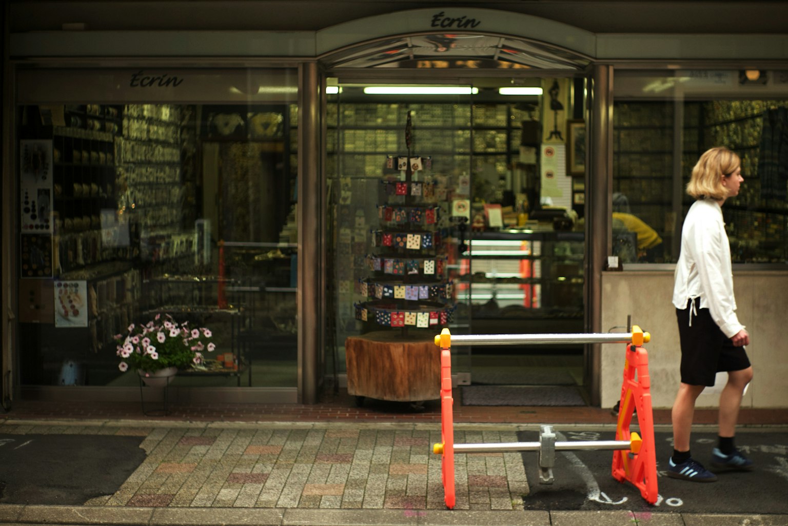 ผู้หญิงเดินผ่านร้านหนังสือที่มีการจัดแสดงหนังสือและดอกไม้