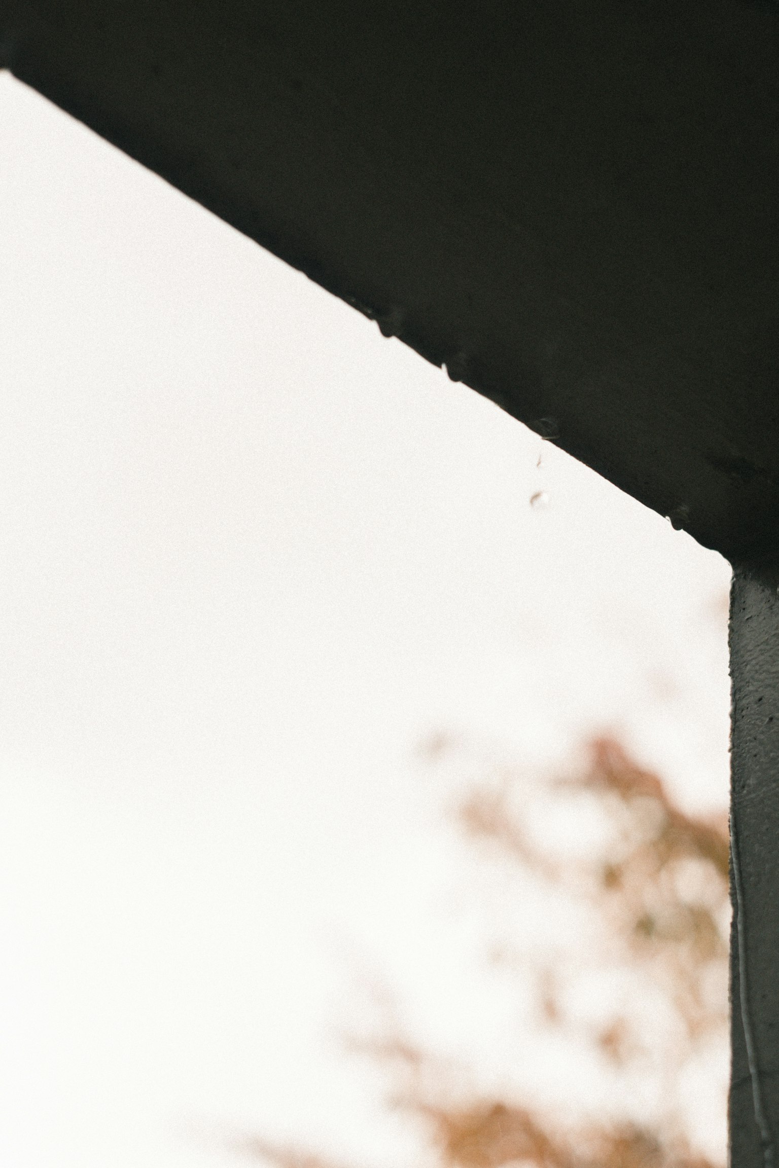 A close-up of a roof edge with water droplets against a cloudy sky