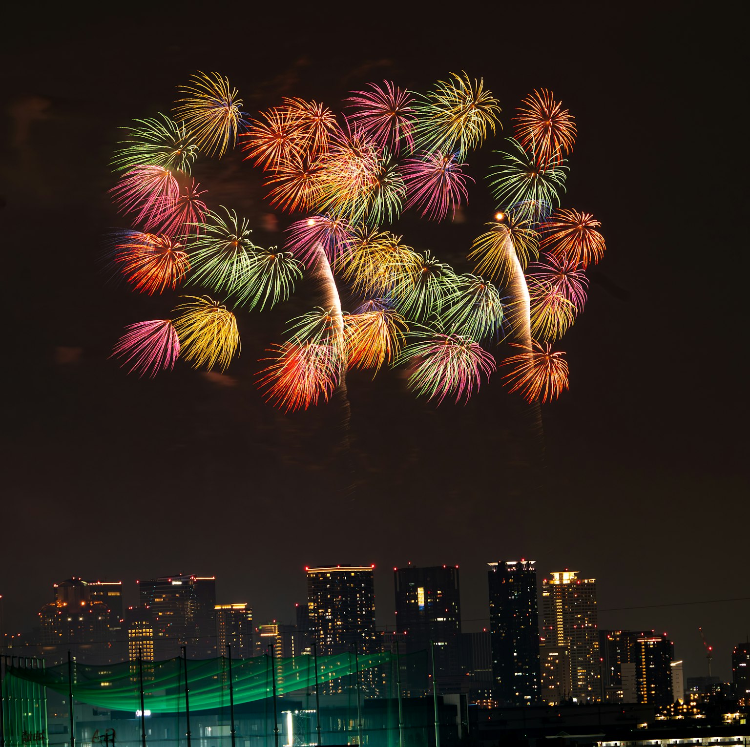 Feux d'artifice colorés fleurissant dans le ciel nocturne au-dessus d'une silhouette urbaine