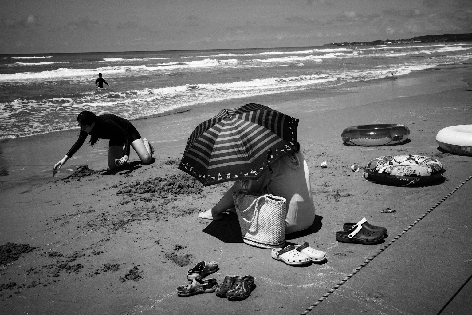 Personas disfrutando de la playa con una mujer bajo un paraguas a rayas